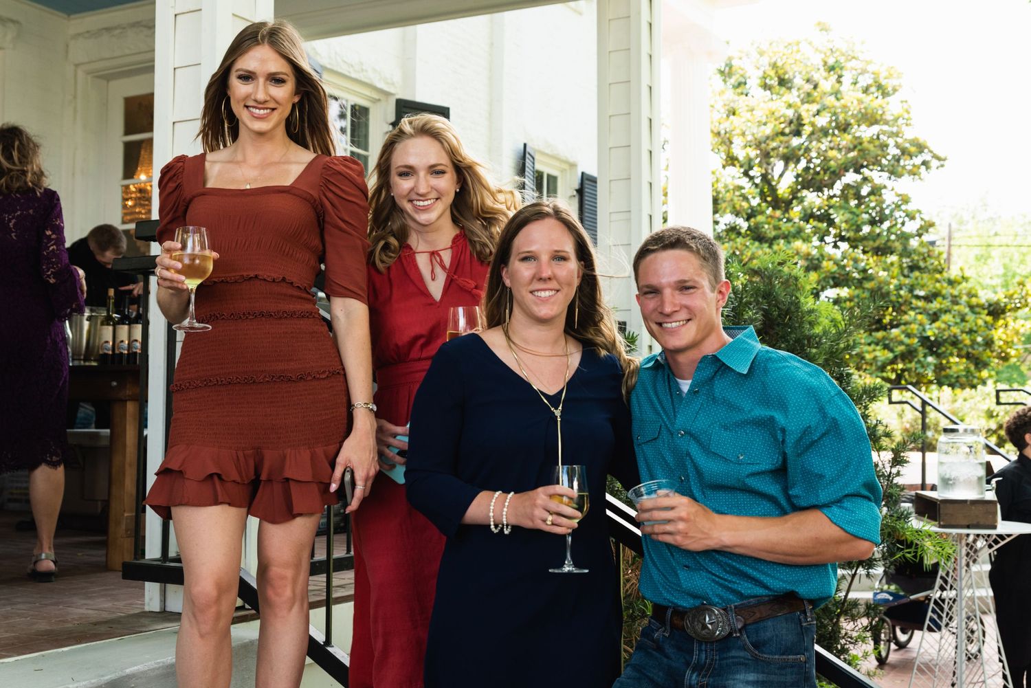Group of wedding guests enjoying drinks on an outdoor patio.