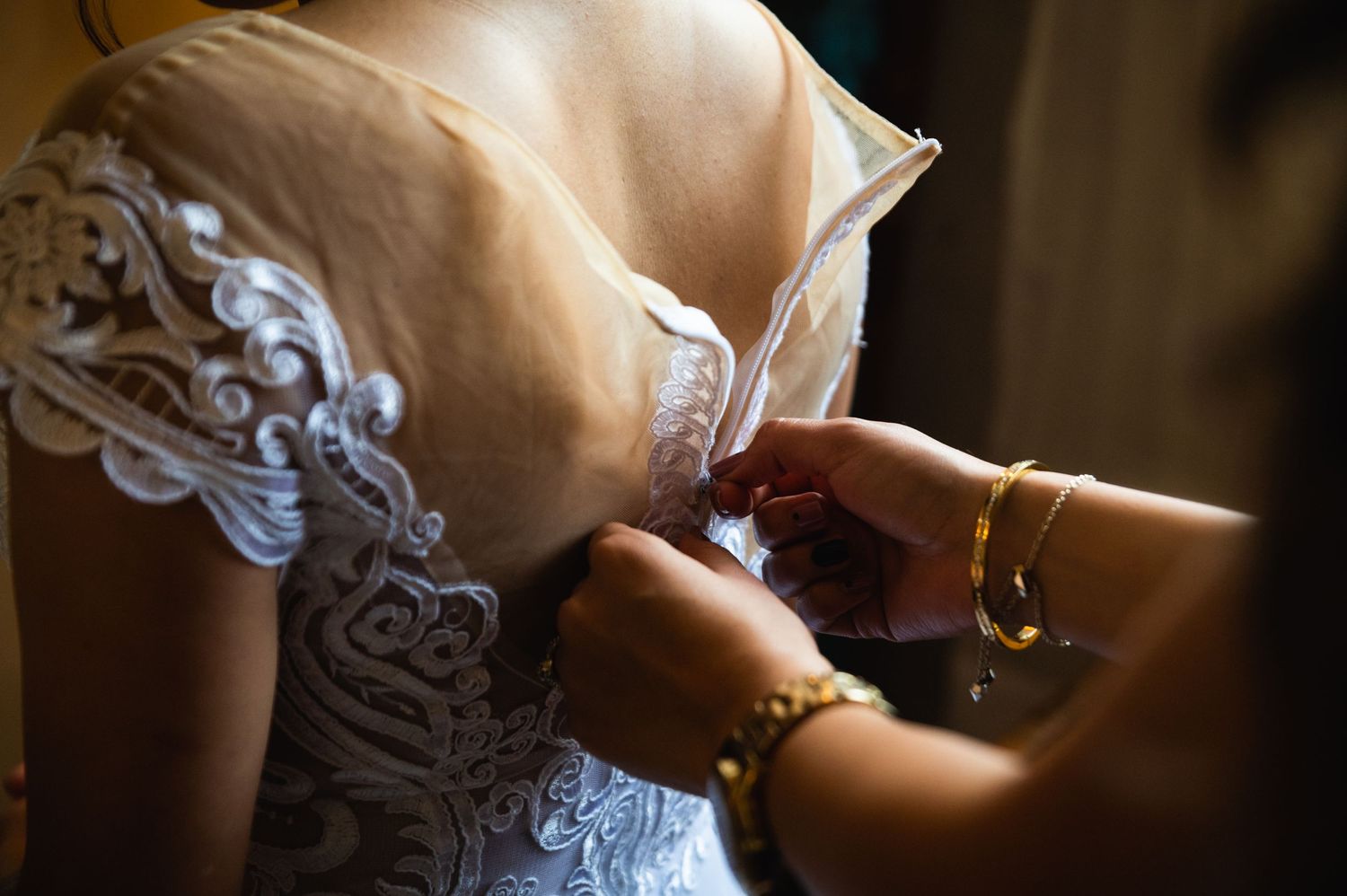 Close-up detail of intricate lace on a wedding dress being fastened.