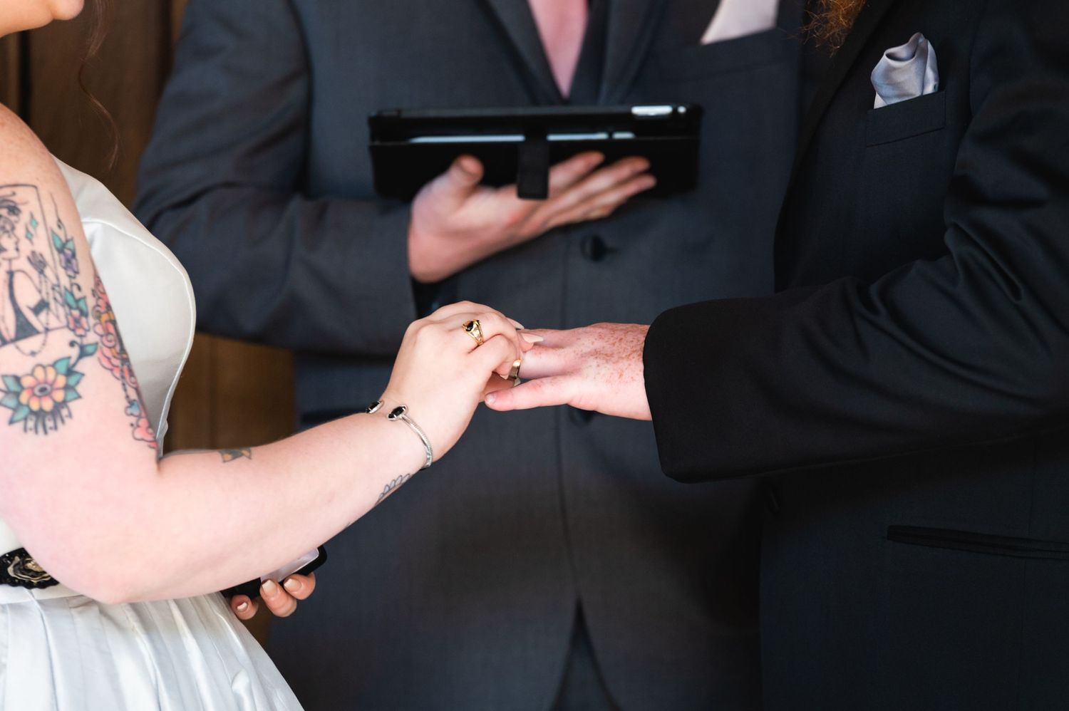 A close-up of hands exchanging rings during a wedding ceremony.