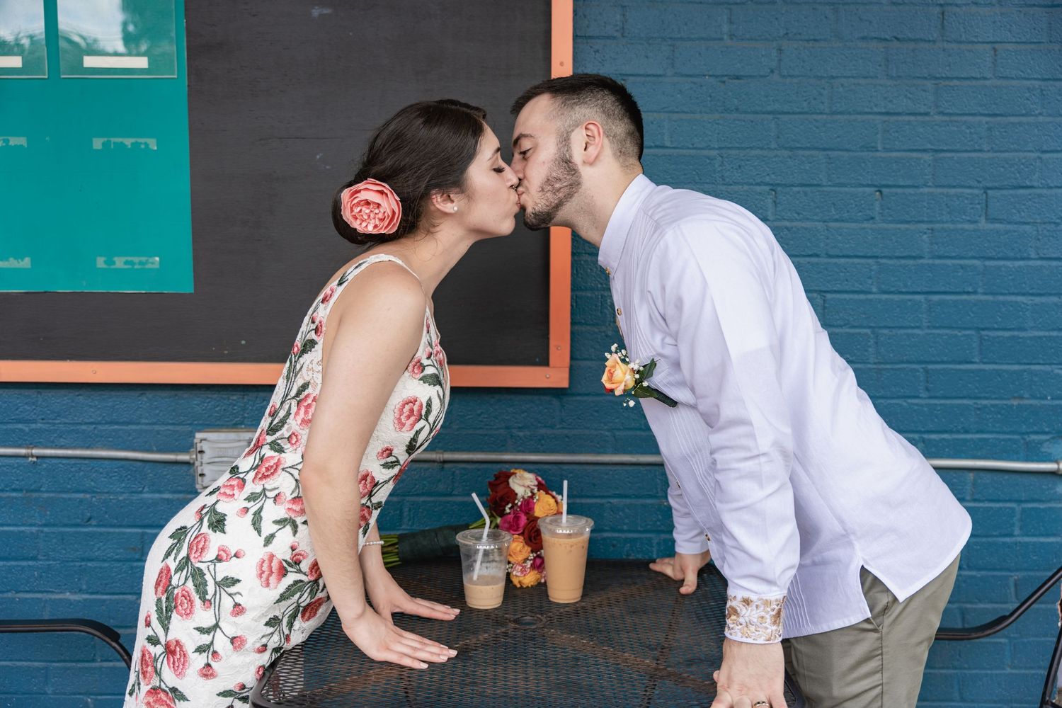 A romantic moment shared between a couple at an outdoor cafe with drinks on the table.