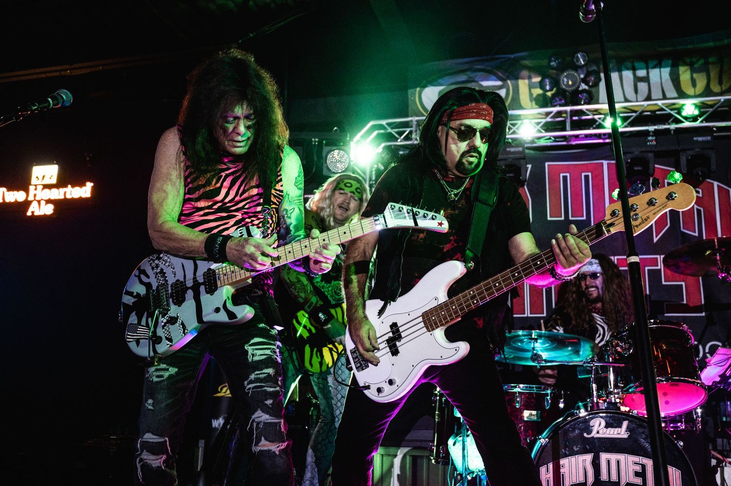 Band members playing guitars during a dimly lit concert performance.