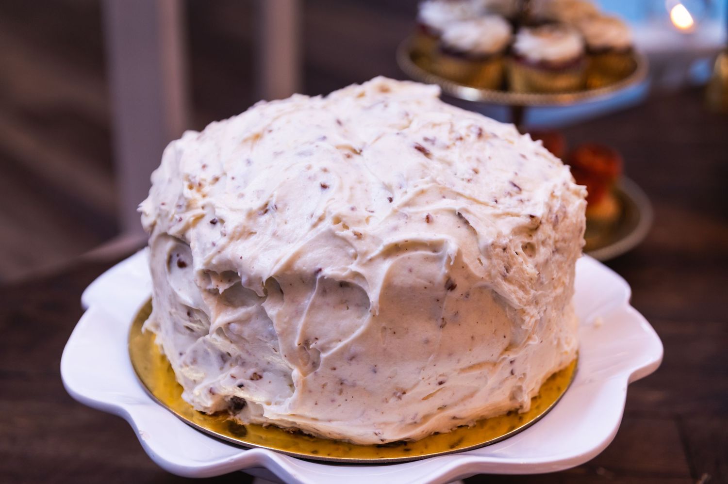 A white frosted cake with textured icing sits on a decorative plate.