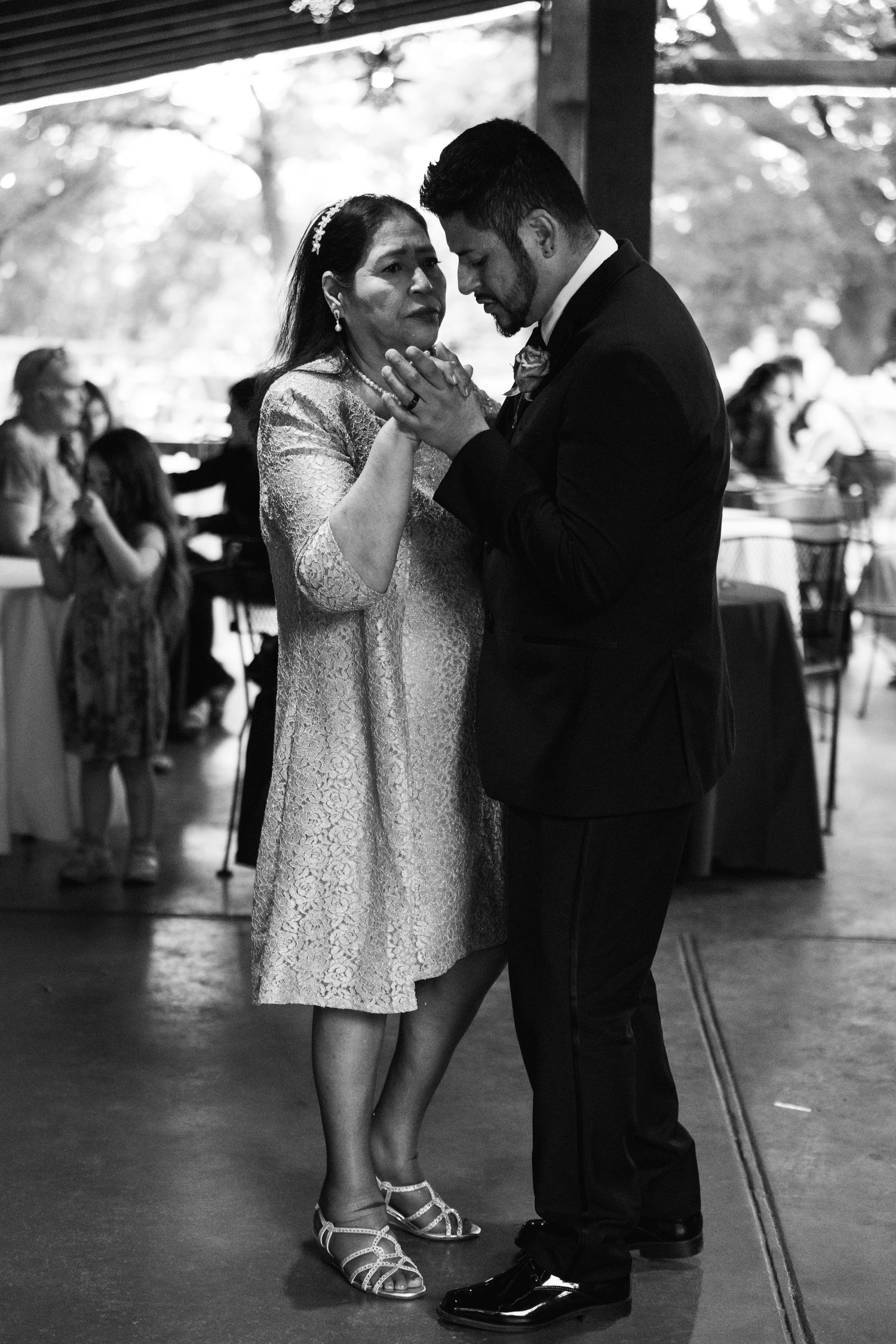 A couple shares an intimate slow dance together at a wedding reception, with the woman wearing a short white dress.