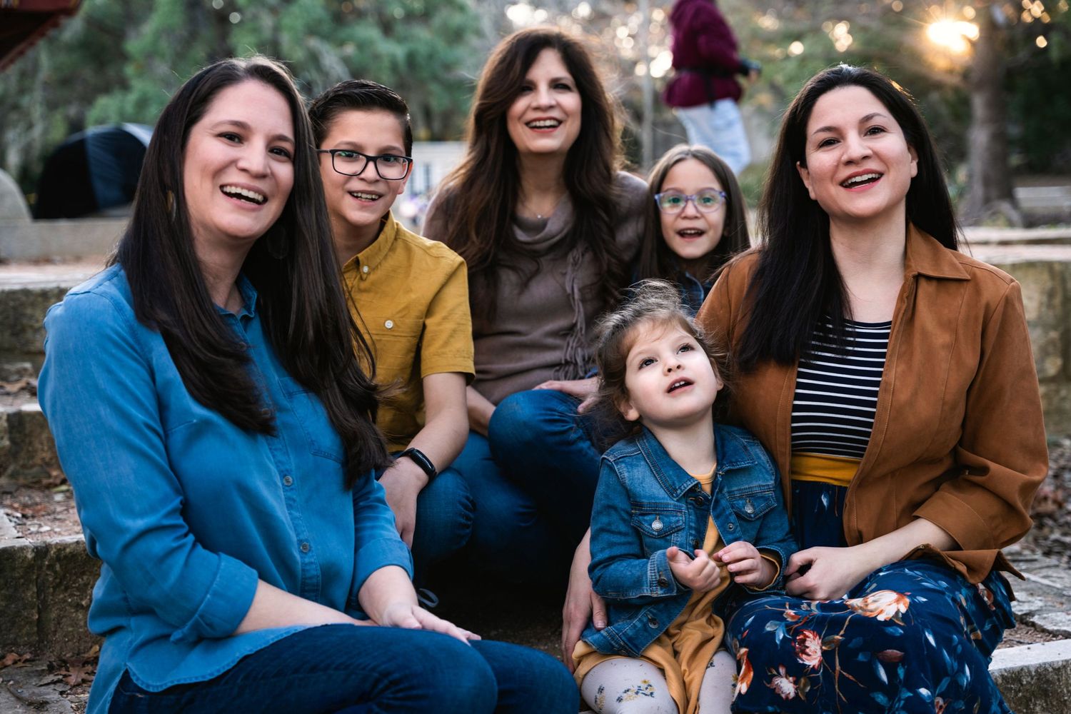 A family group sitting together outdoors on stone steps during sunset.