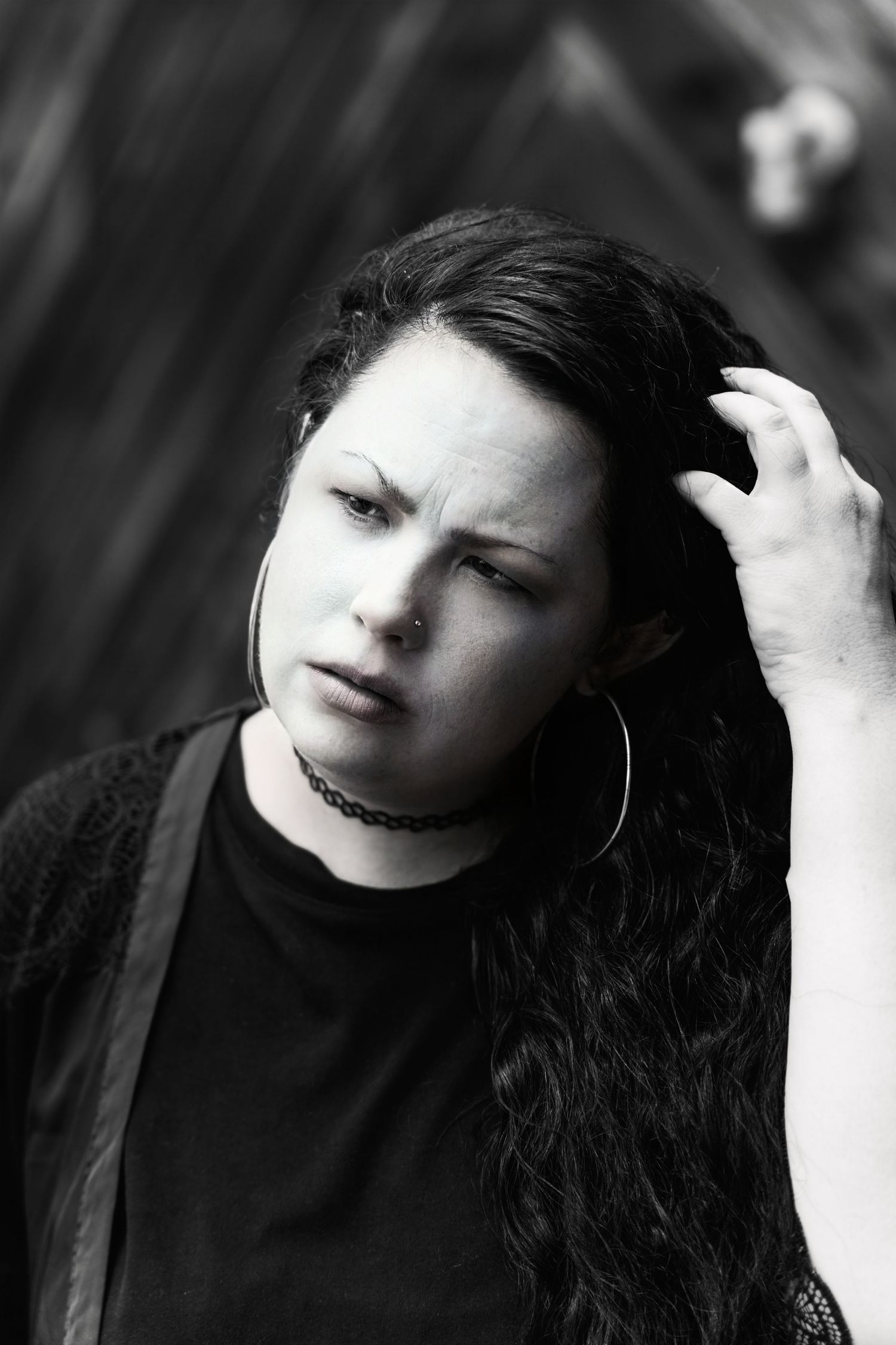 Black and white portrait showing contemplative expression with hand in dark hair.