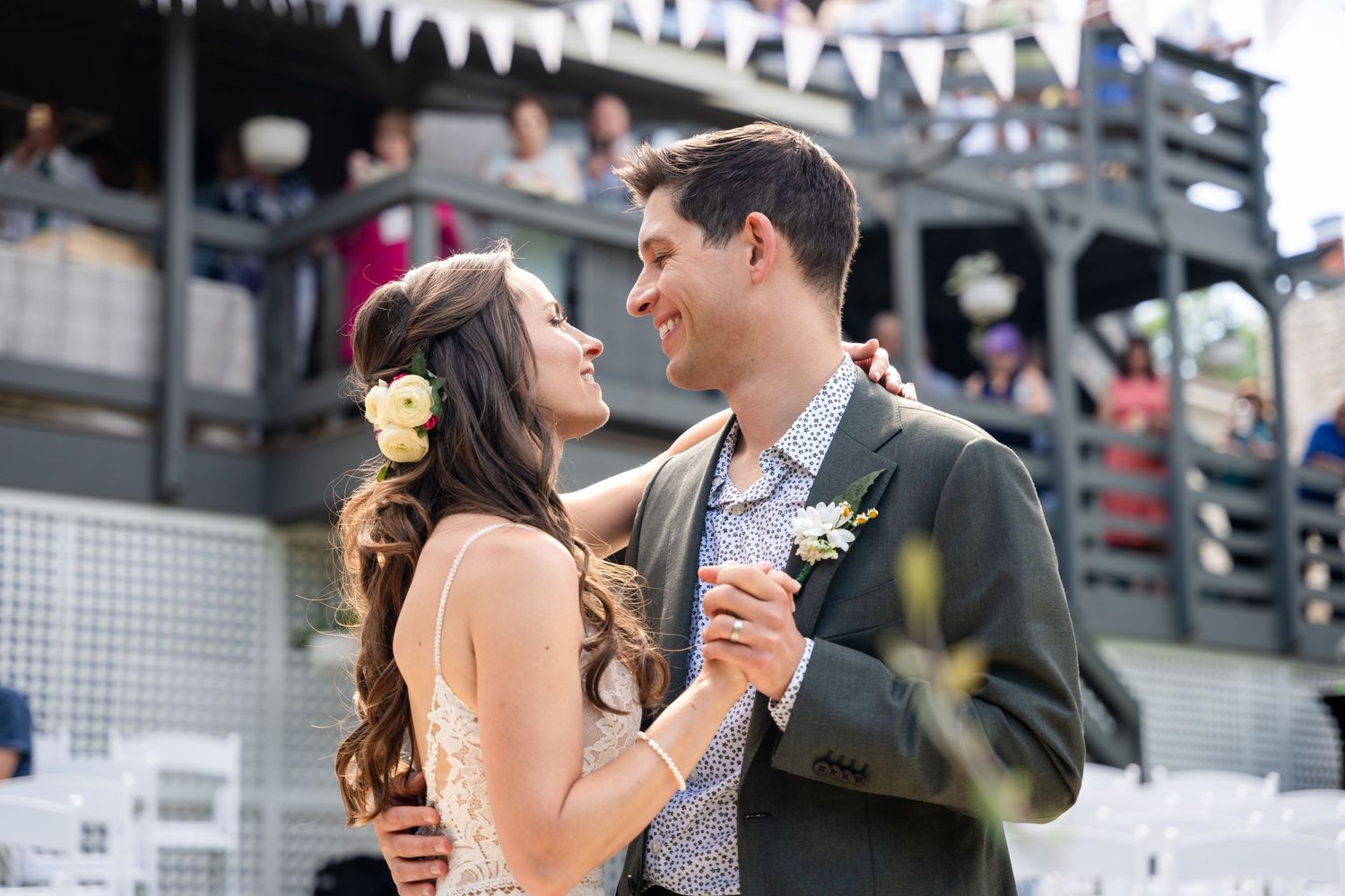 A romantic dance moment at an outdoor celebration with decorative bunting overhead.