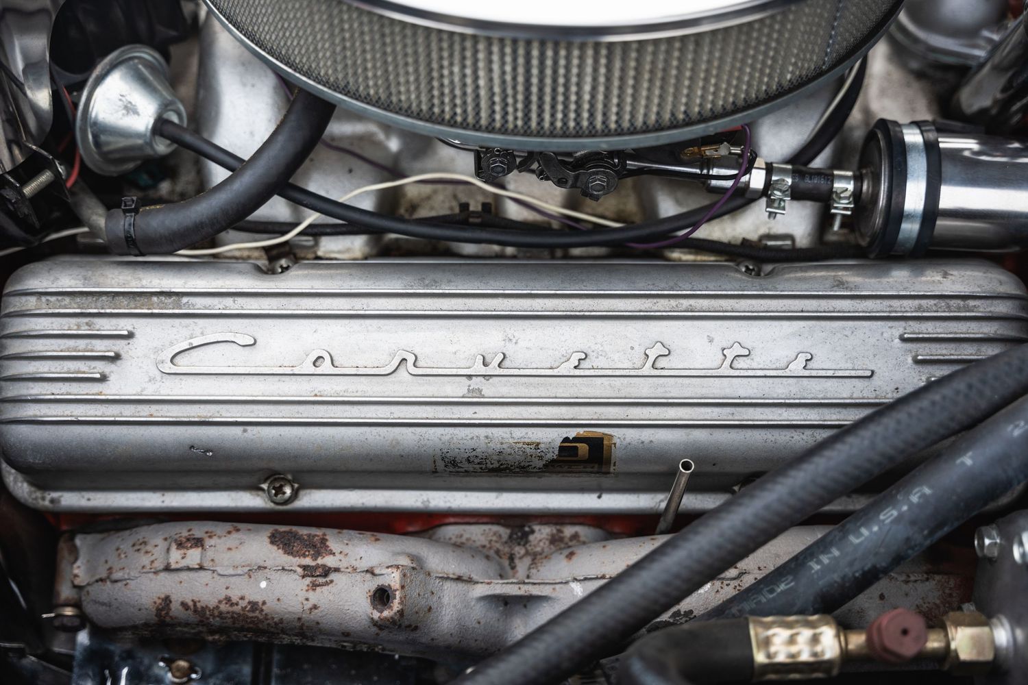Close-up of a Corvette engine bay showing vintage valve covers and air cleaner.
