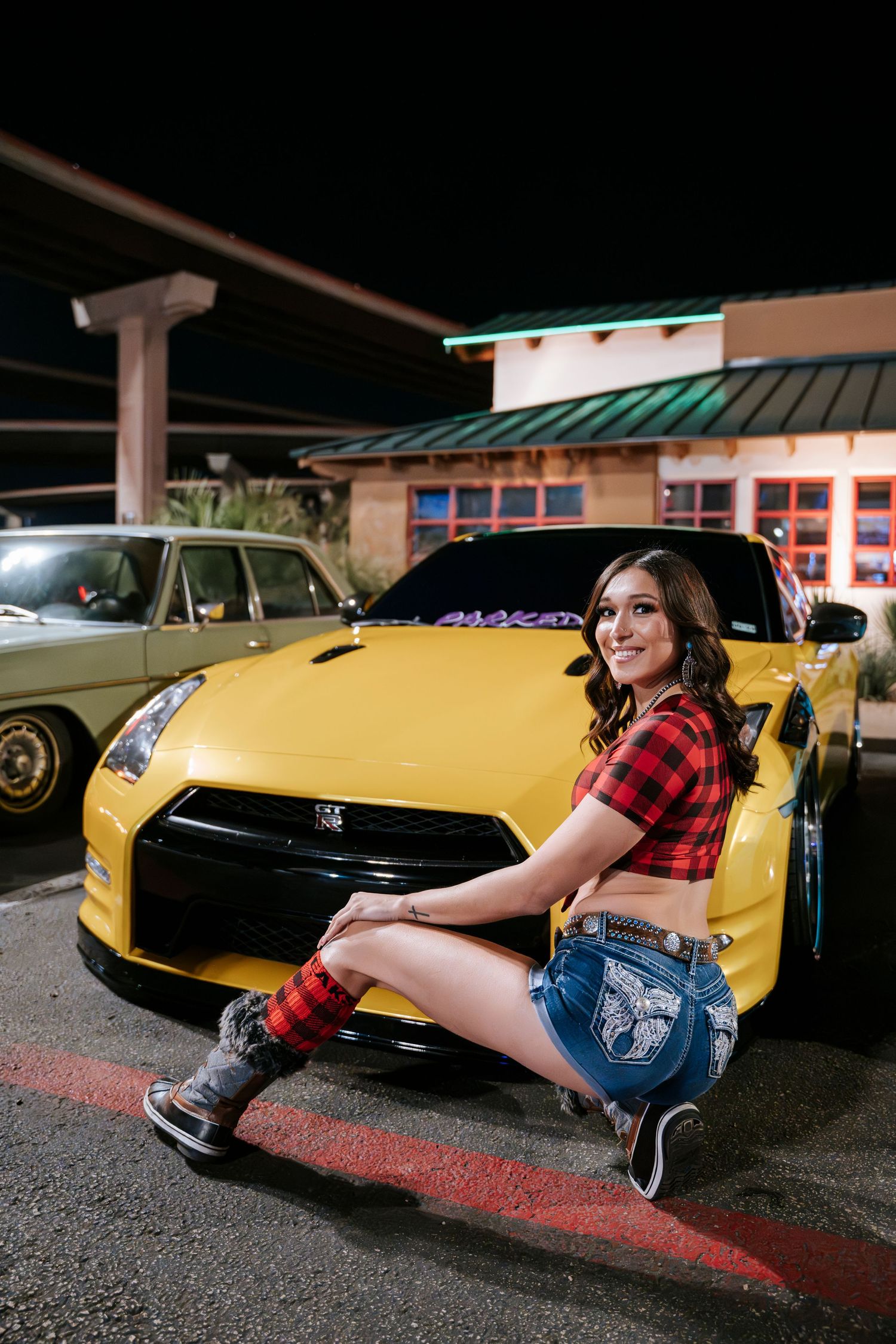 A yellow Nissan GT-R sports car parked outside a restaurant at night.