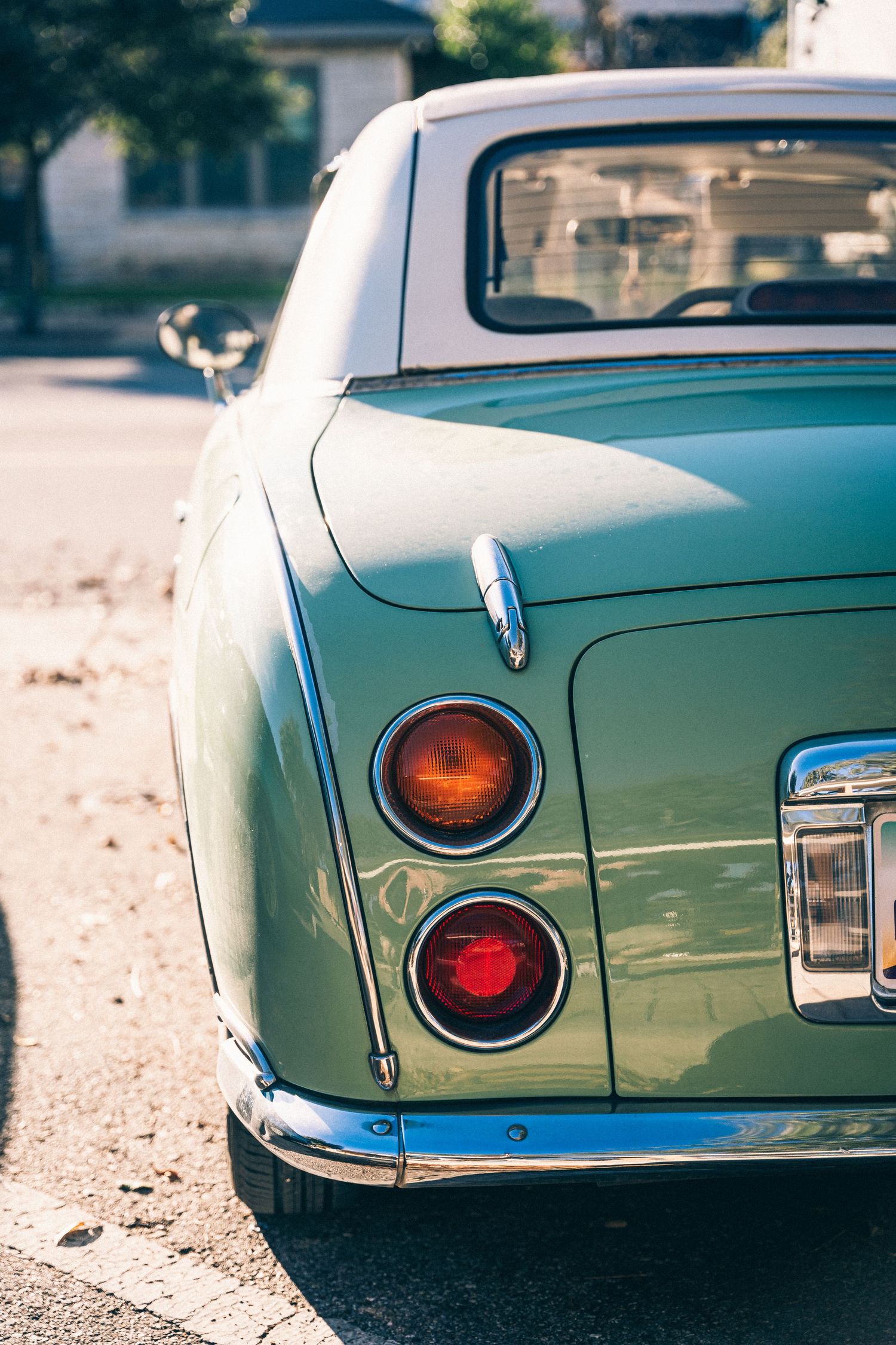 Vintage mint green car showing detailed rear tail lights and chrome trim.