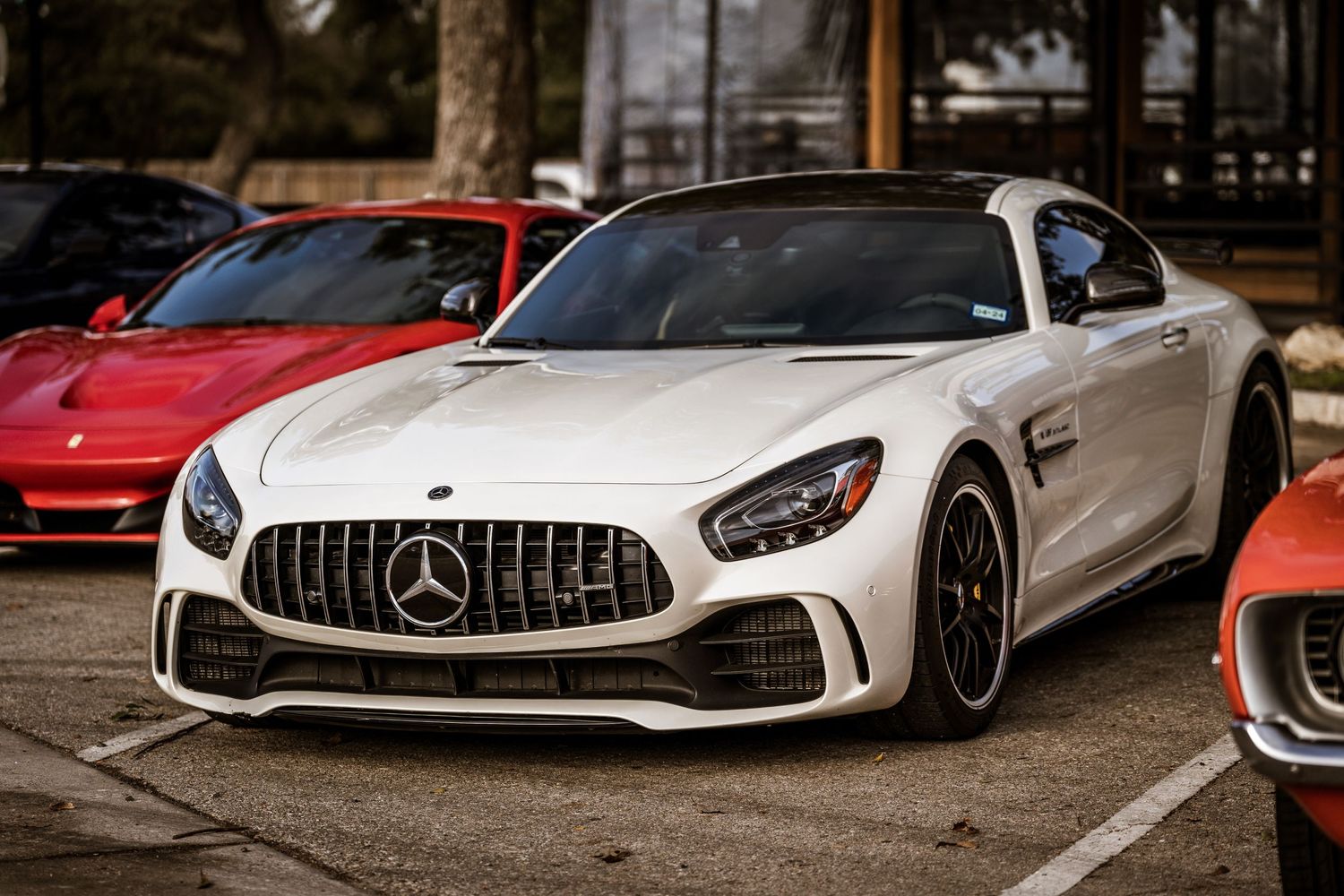 White Mercedes-AMG GT sports car with aggressive front grille parked at a car show.