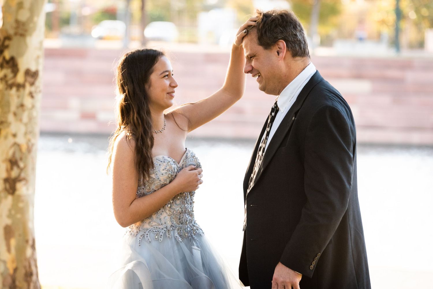 A romantic formal portrait showing a couple in elegant attire posing by a tree.