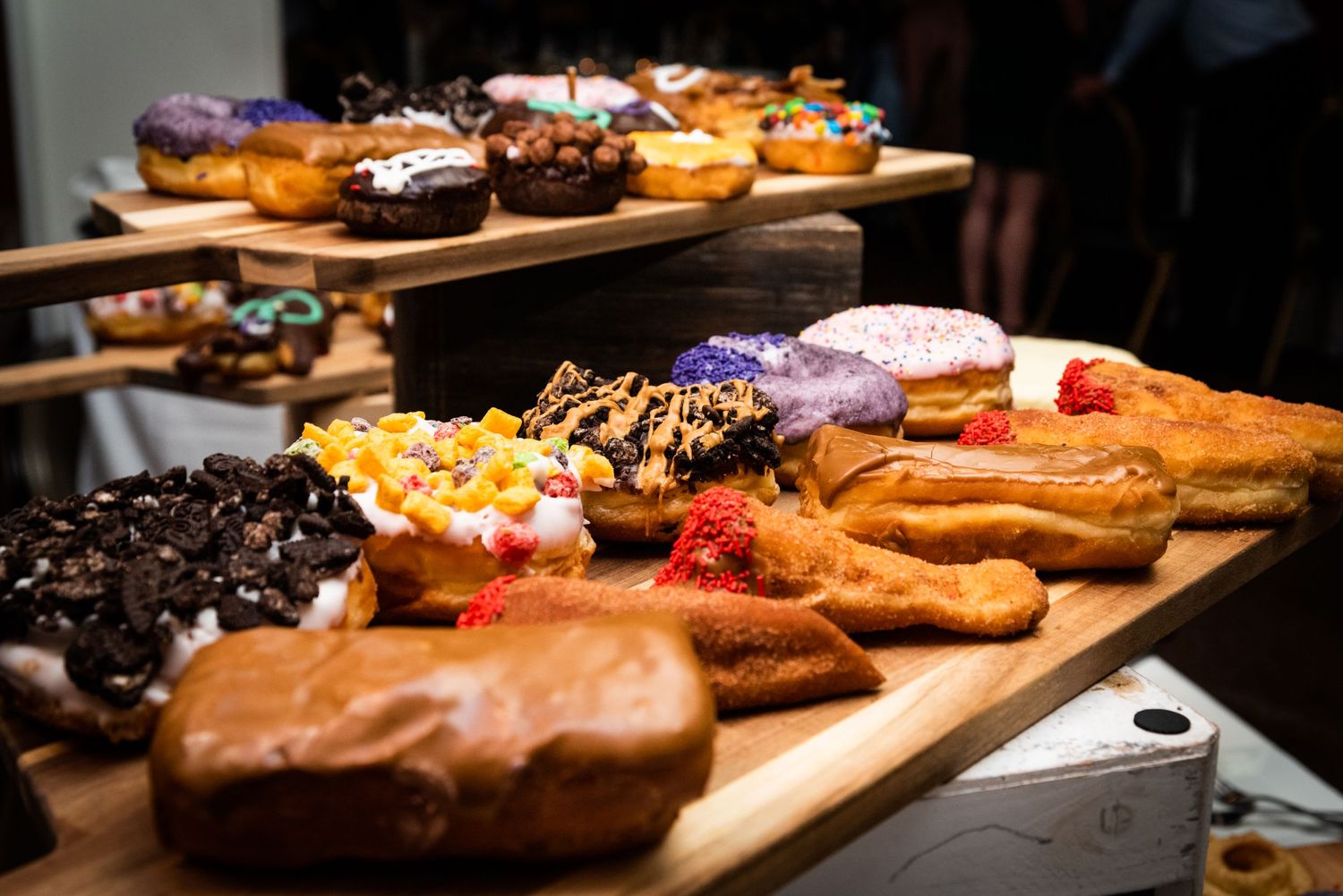 An assortment of colorful donuts and pastries displayed on a wooden serving board.