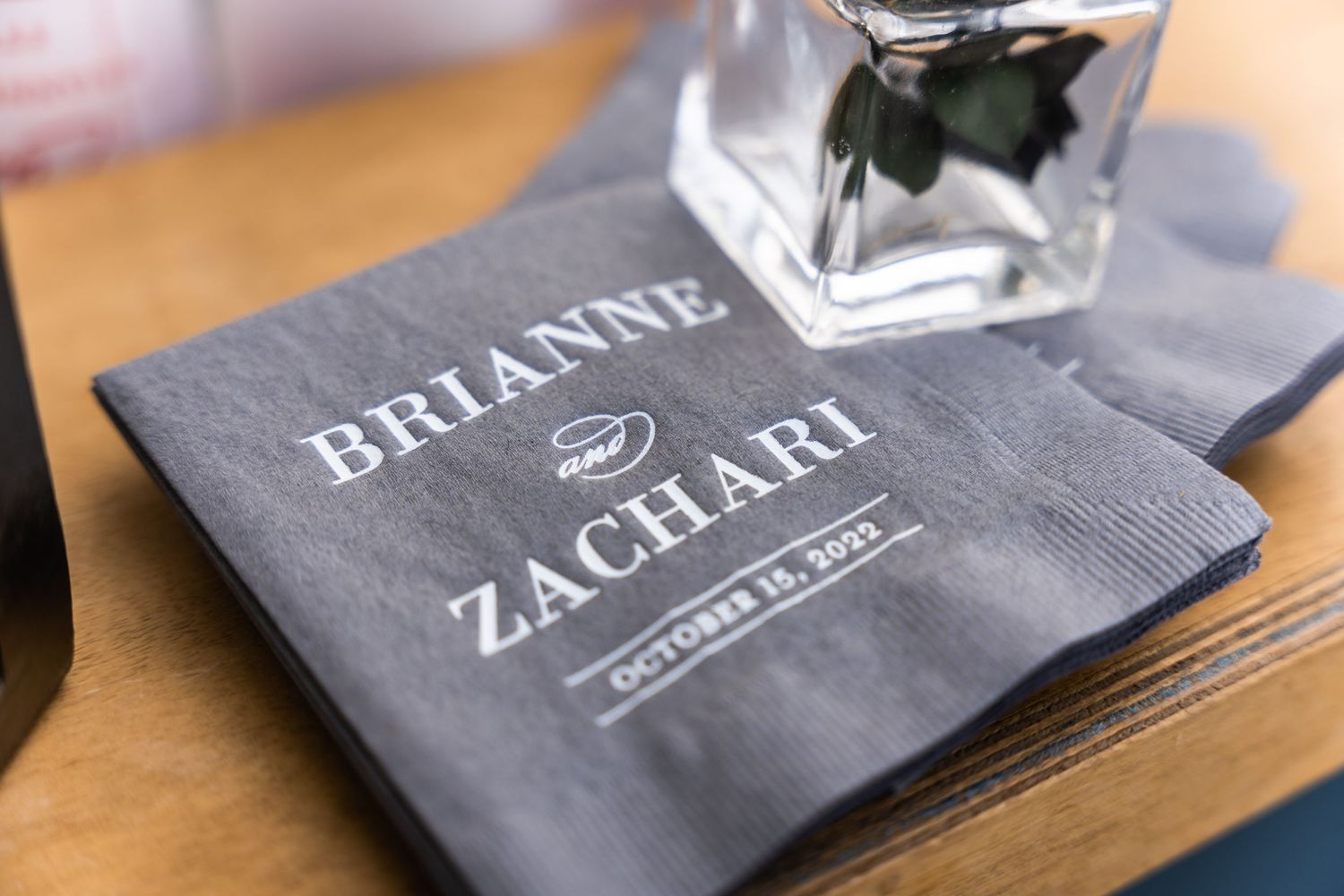 Gray wedding napkin with couple's names 'Brianne and Zachari' printed in elegant typography.