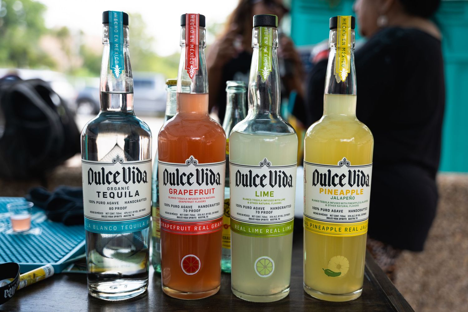 Four bottles of Dulce Vida tequila in different flavors lined up on a table.