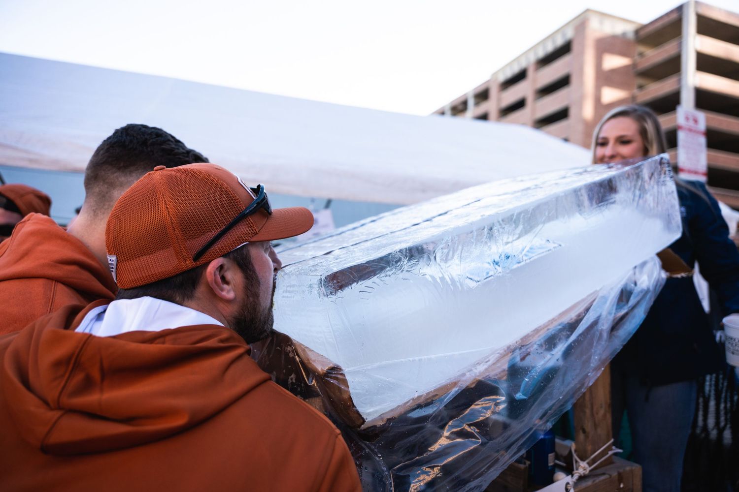 Attendees enjoy drinks from an ice luge with a parking structure visible in the background.