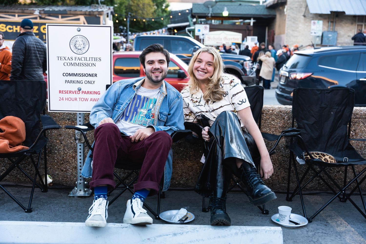 Two people sitting on a bench outdoors near event signage.