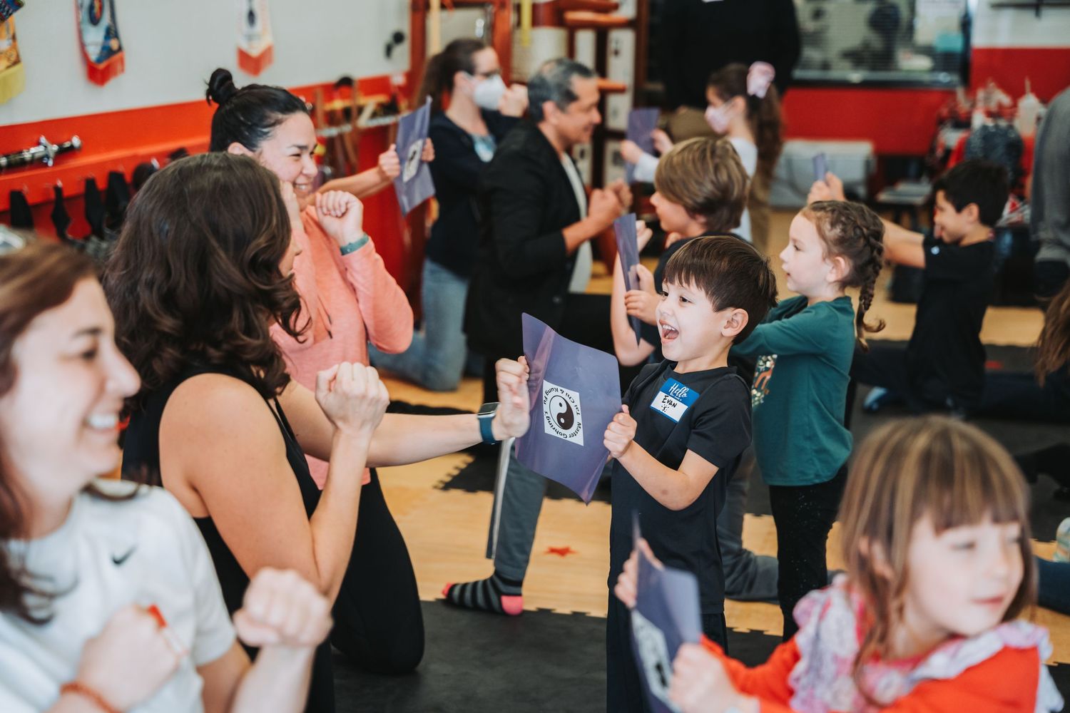 Group martial arts class with students and instructors practicing defense techniques.