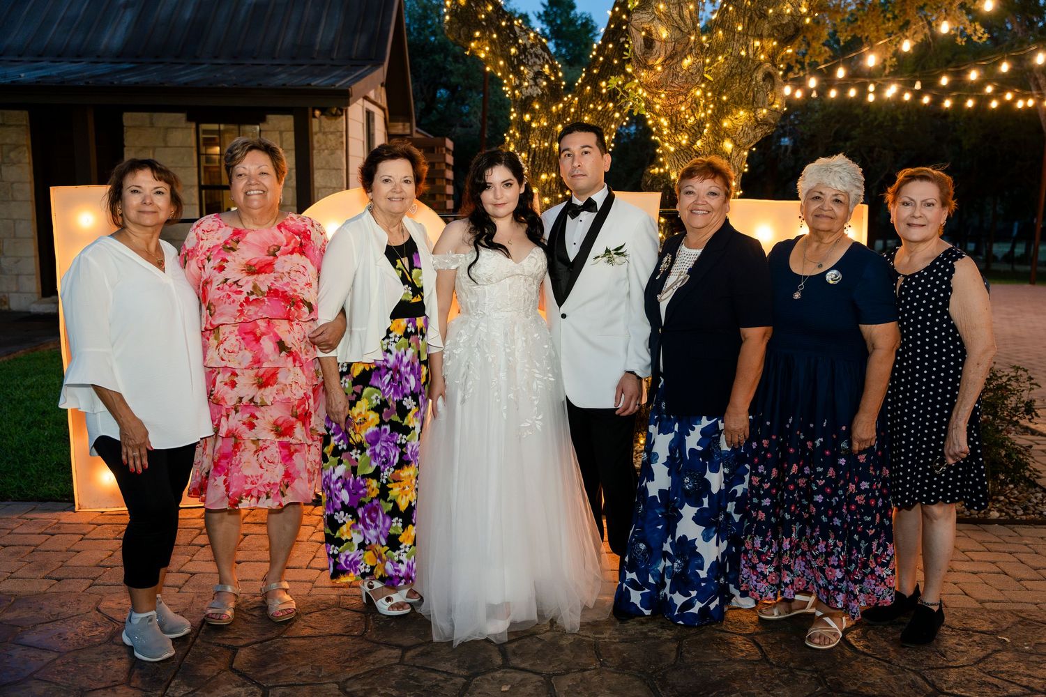 Guests gathered at golden-hour during an outdoor wedding celebration with string lights illuminating the space.