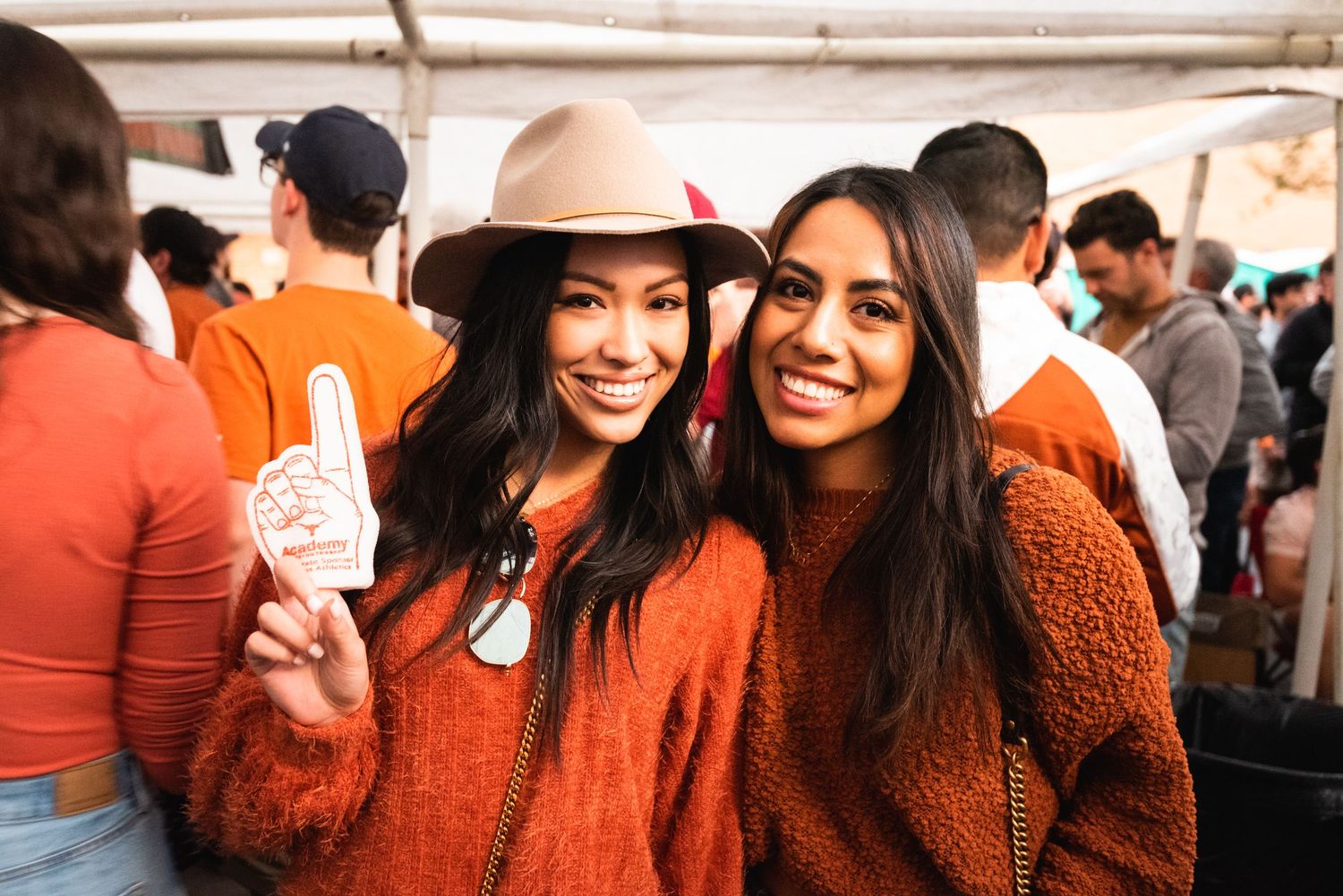 Group of people wearing matching burnt orange outfits gather together at an outdoor event.