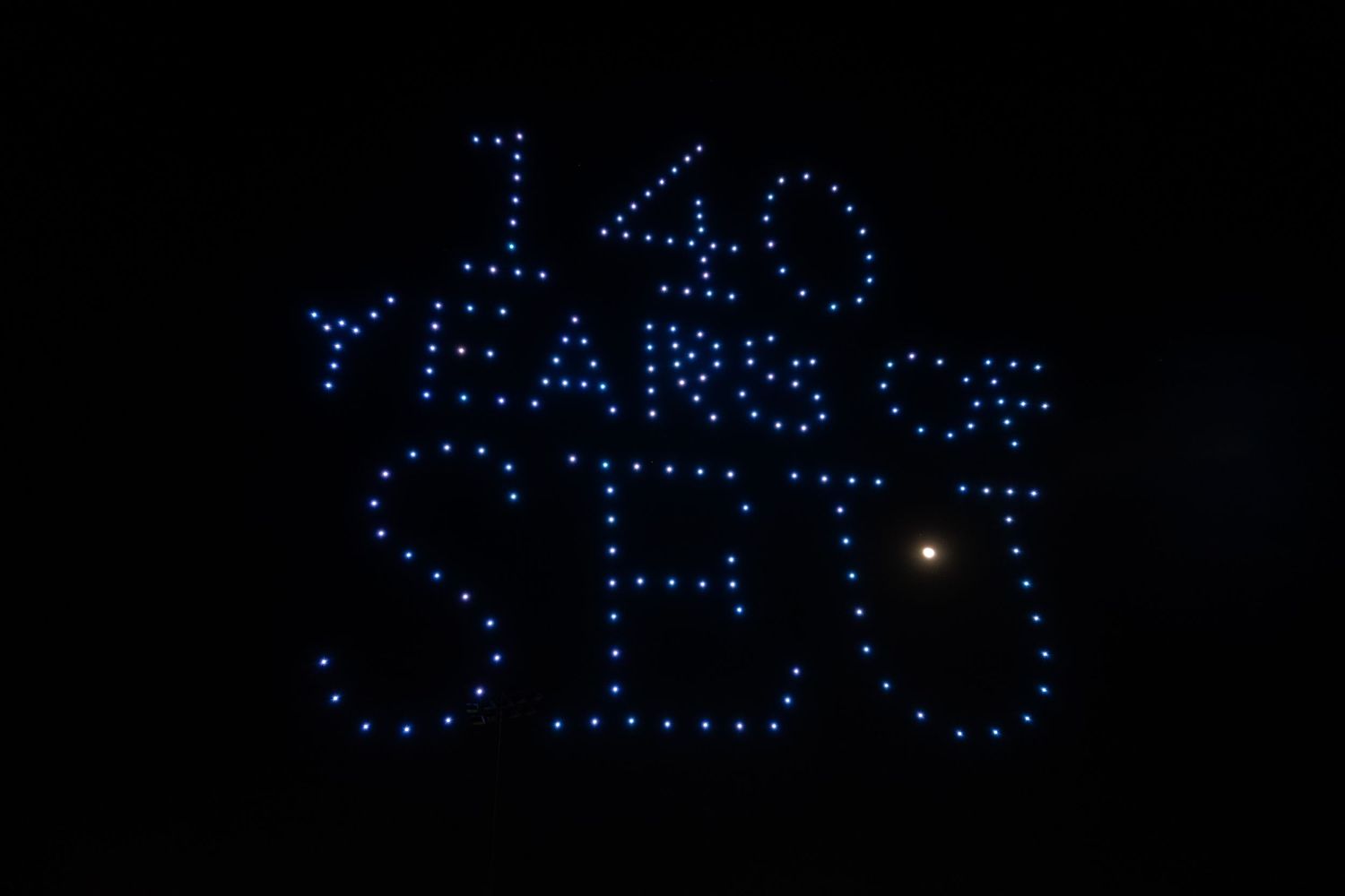 Decorative blue LED lights spelling out text against a dark background with a bright star visible in the night sky.