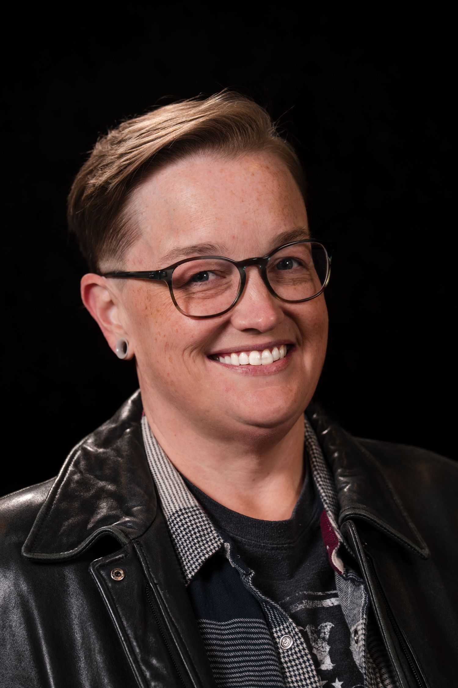 A series of black and white headshots showing someone wearing glasses and a leather jacket against a dark background.