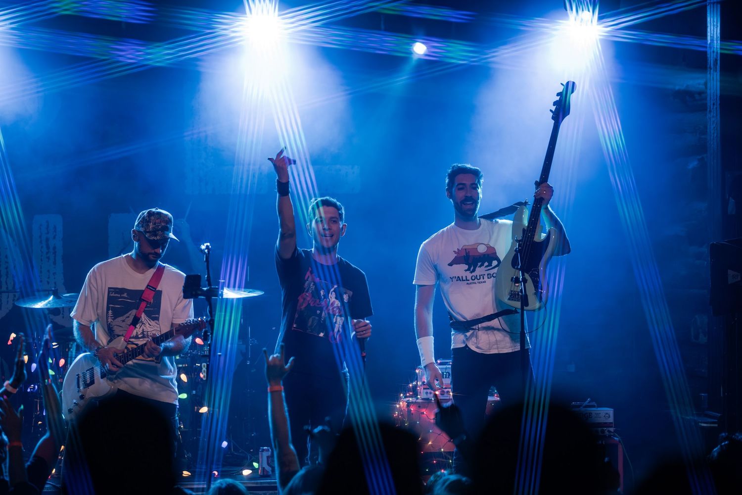 Musicians perform on stage with dramatic blue lighting and fog effects during a concert performance.