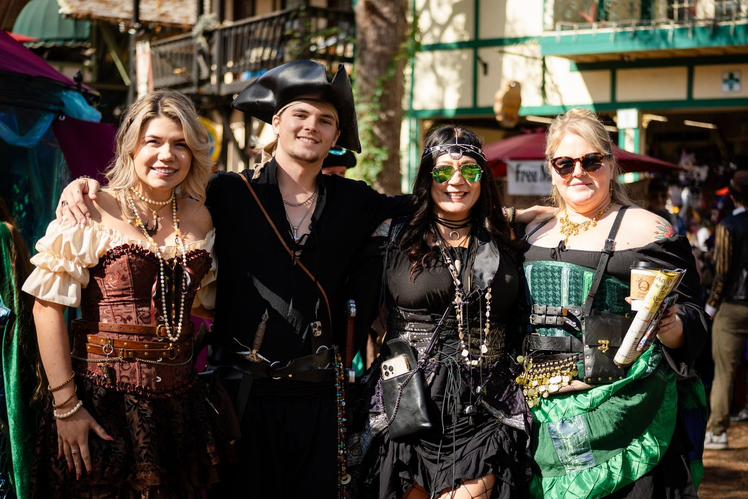 Group of people in steampunk and gothic costumes posing together at an outdoor event.