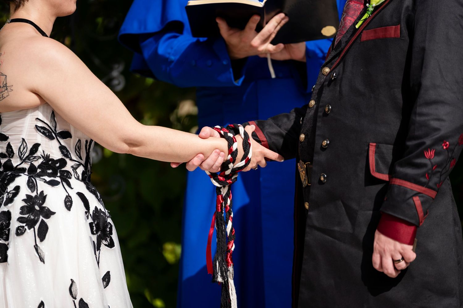 Couple exchanging rings during an outdoor wedding ceremony with blue and floral decor.