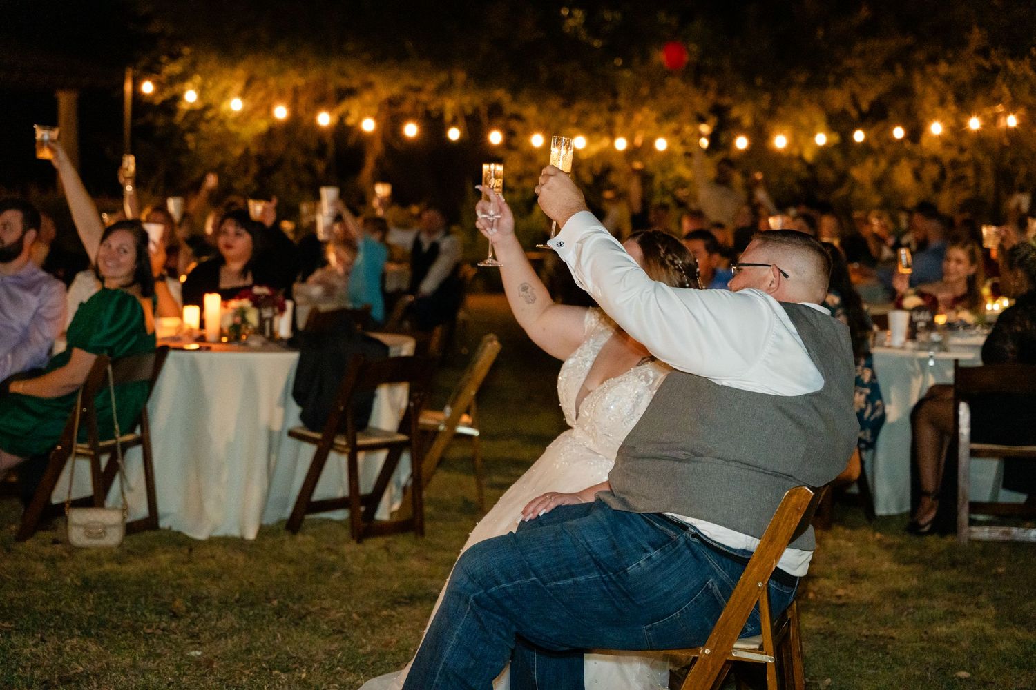 Wedding guests celebrating under string lights at outdoor reception.