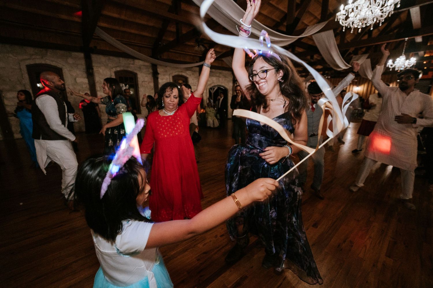 Guests dancing energetically under white draping at a lively indoor celebration.