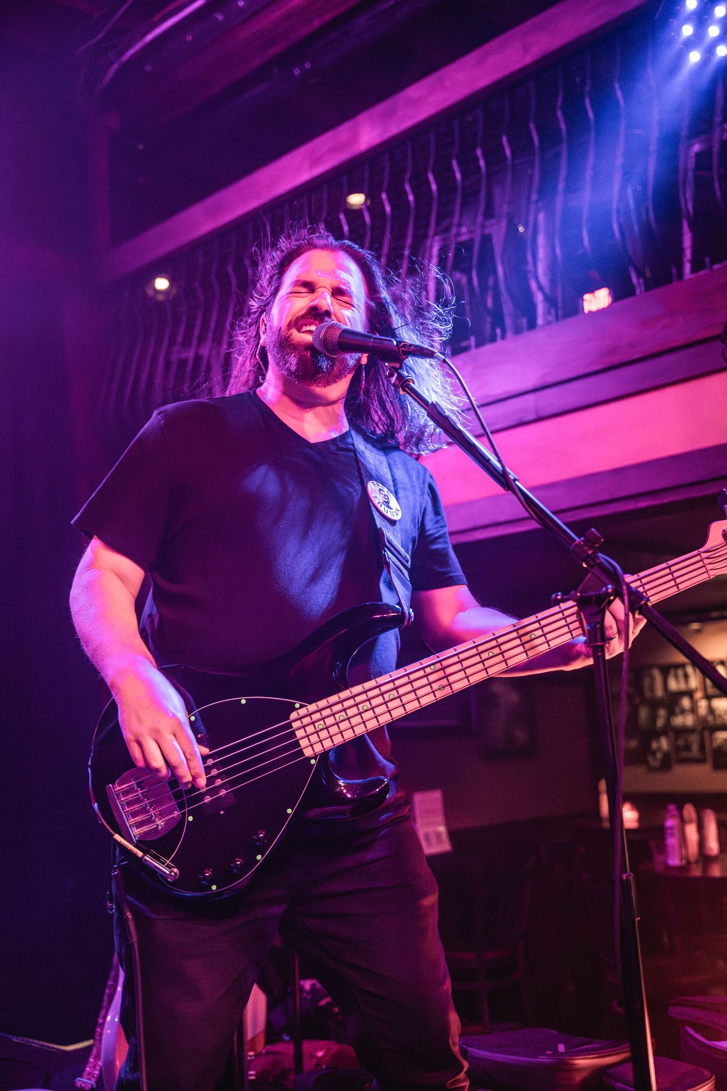 Bassist performing on stage with vibrant purple and blue lighting effects.