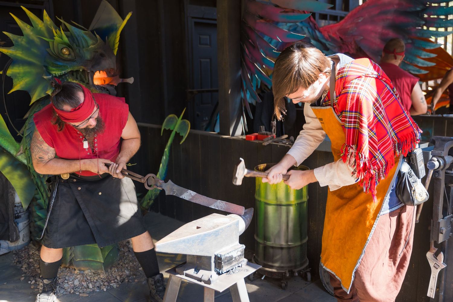 Workers preparing crafts and goods at a rustic outdoor festival booth.