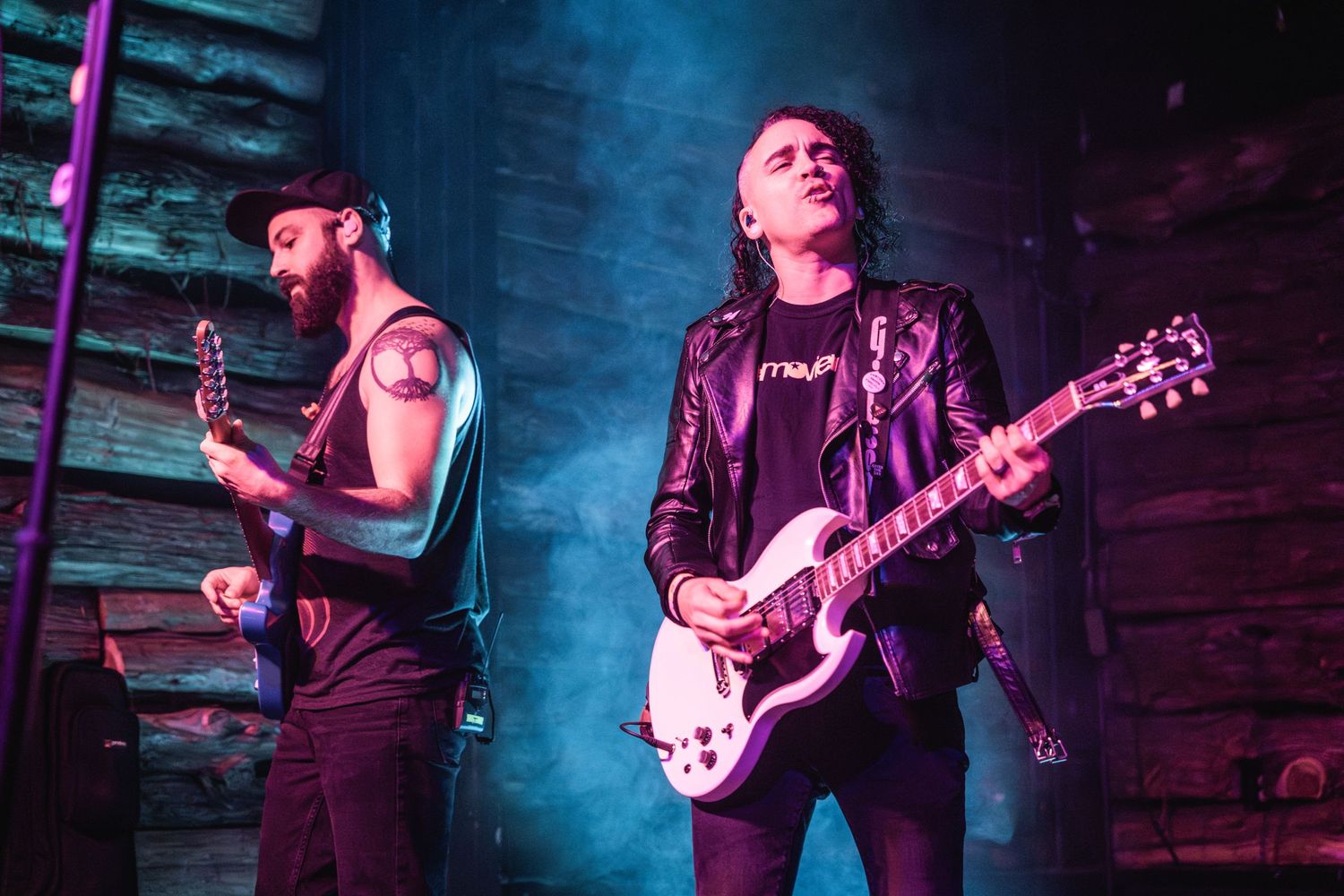 Two band members performing onstage with atmospheric blue lighting.