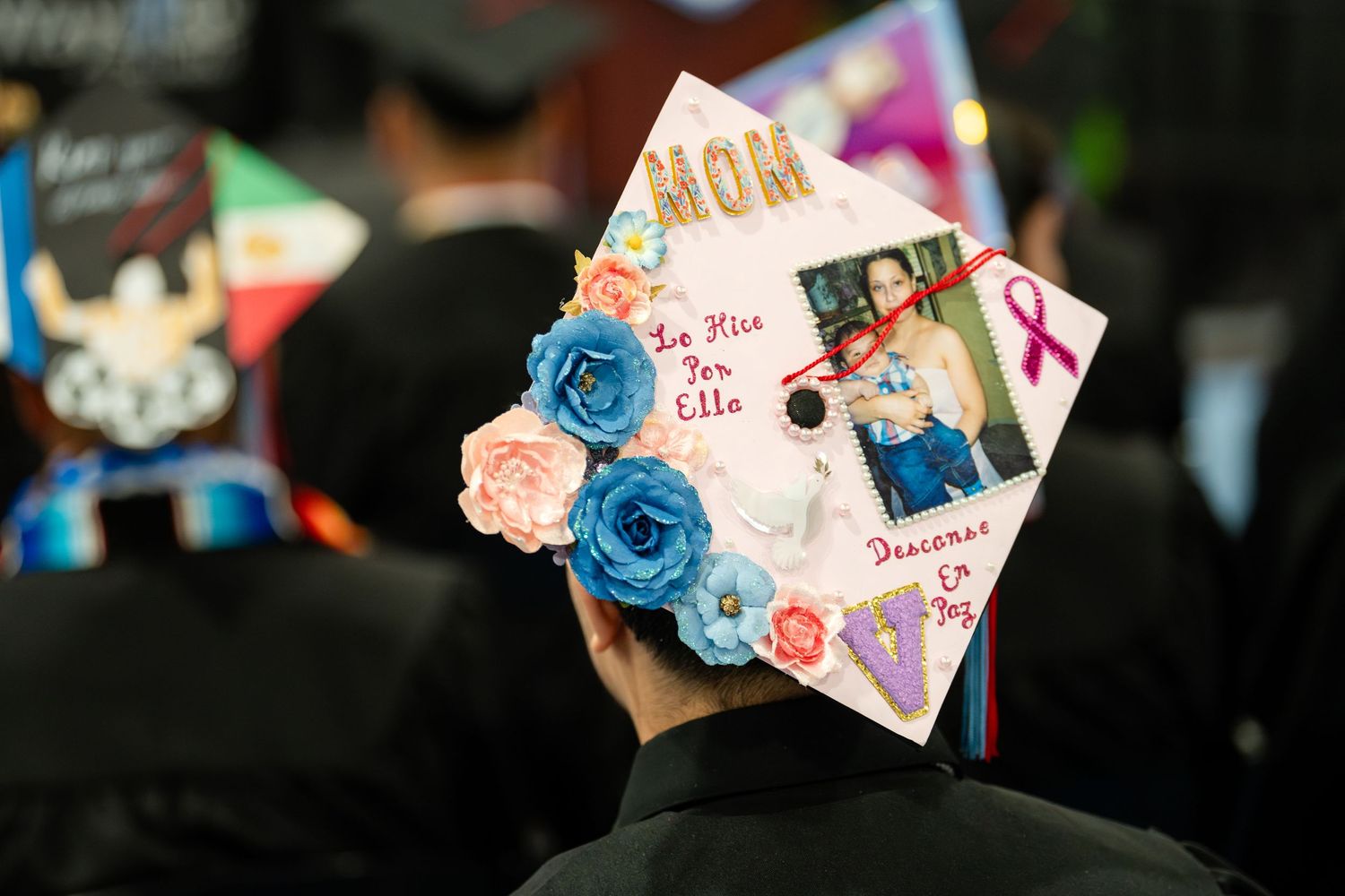 Graduation cap decorated with blue roses and photos in a personal tribute design.