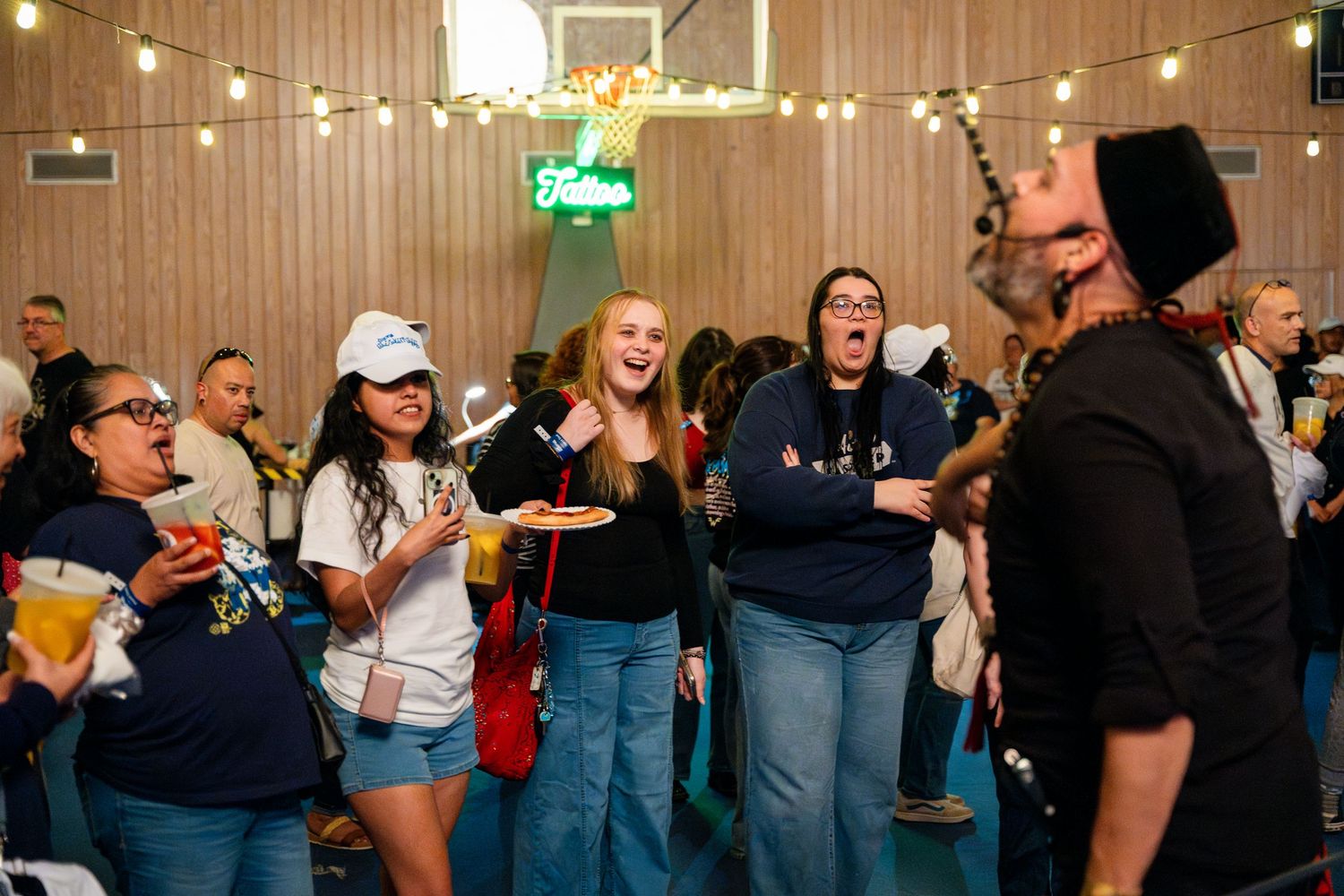 People enjoying a social gathering under string lights in a casual indoor venue, singing and having fun together.
