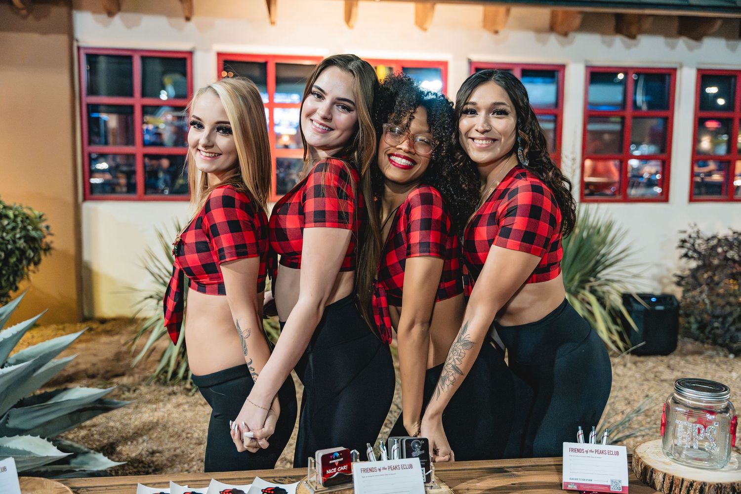 Group photo of matching red plaid crop tops and dark pants at a casual outdoor gathering.