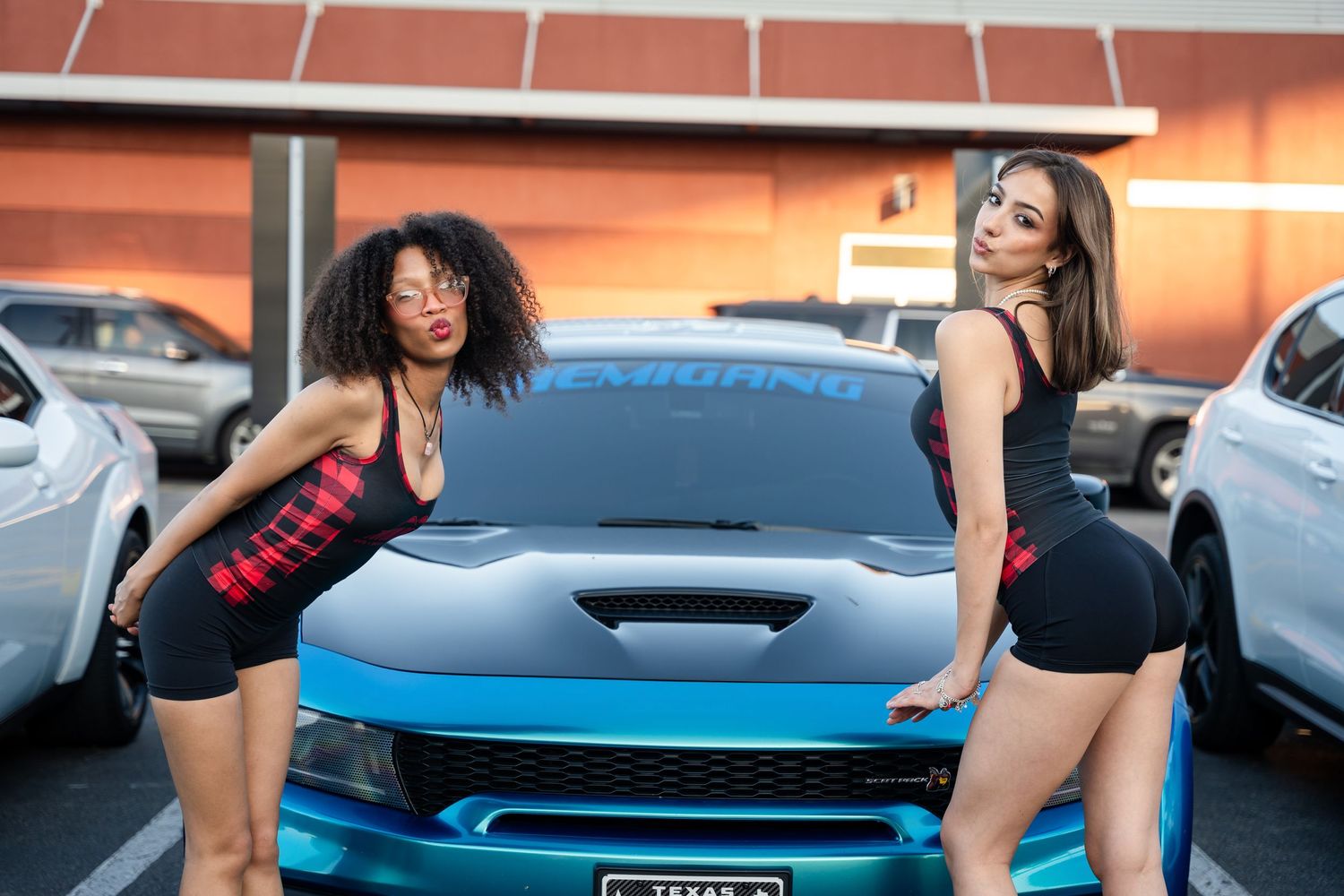 Friends posing playfully in front of a bright blue car in a parking lot.