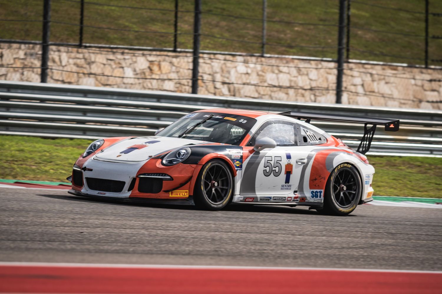 Porsche GT3 race car in white and red livery racing on a professional circuit.