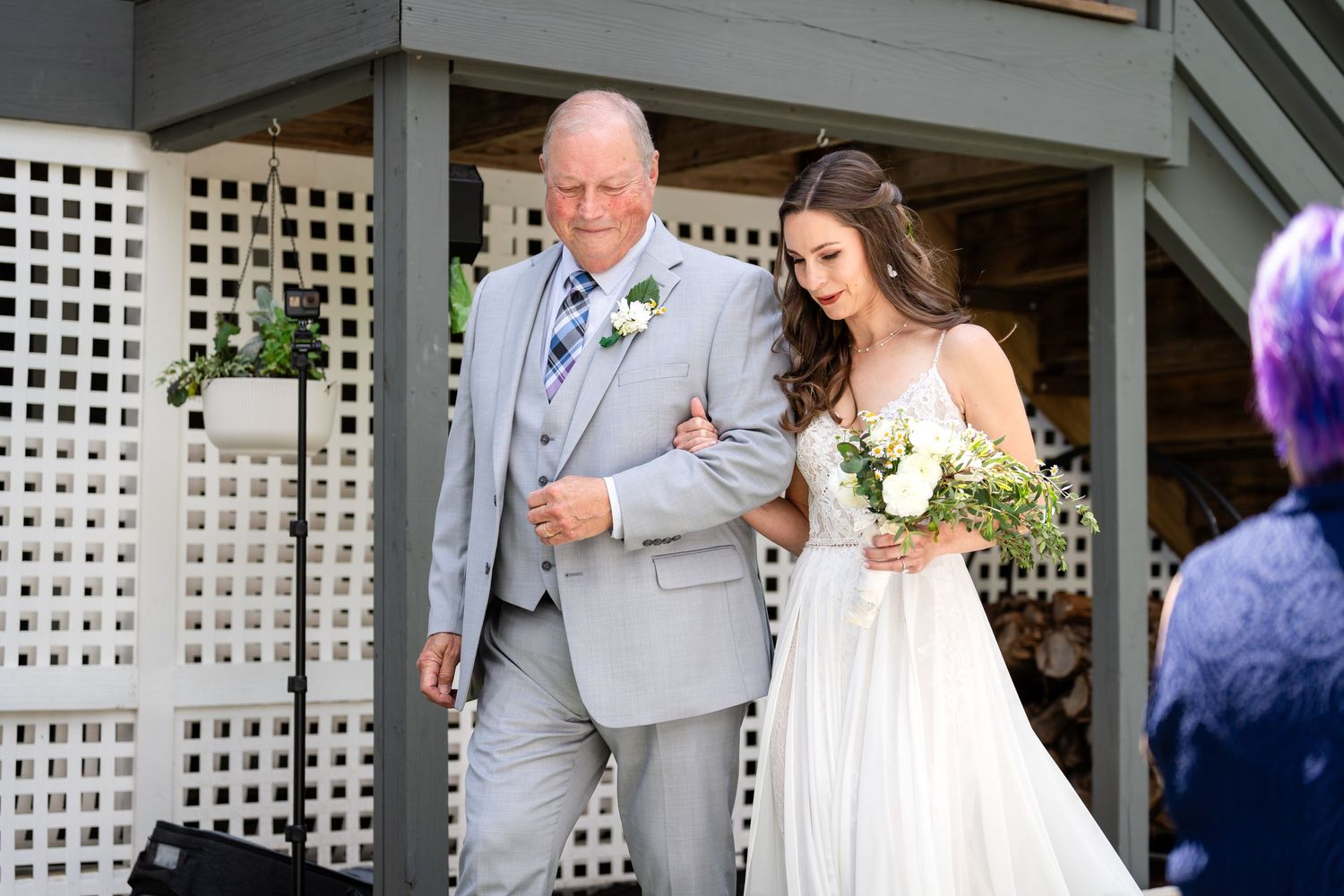 Couple emerges from white latticed venue entrance at outdoor wedding.