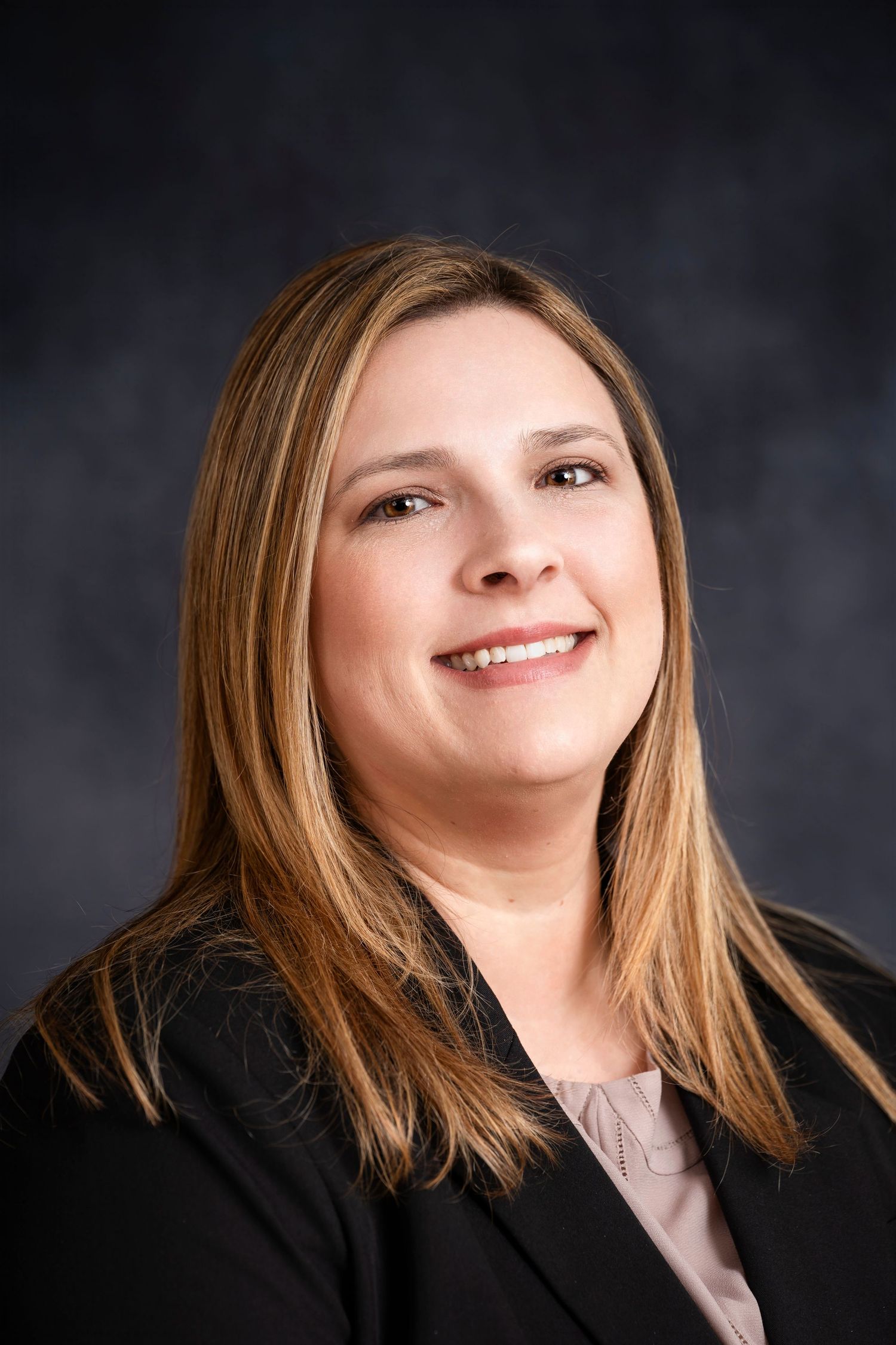 Studio headshot of a businesswoman with light hair wearing professional attire.