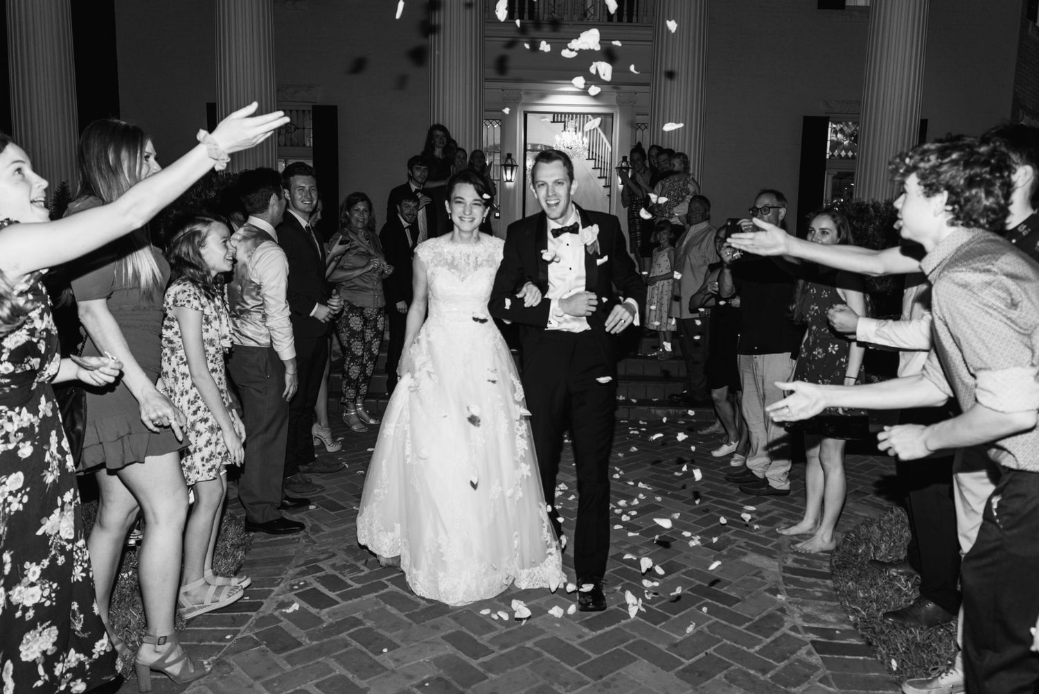Newlyweds exit through a shower of confetti in a black and white wedding photo.
