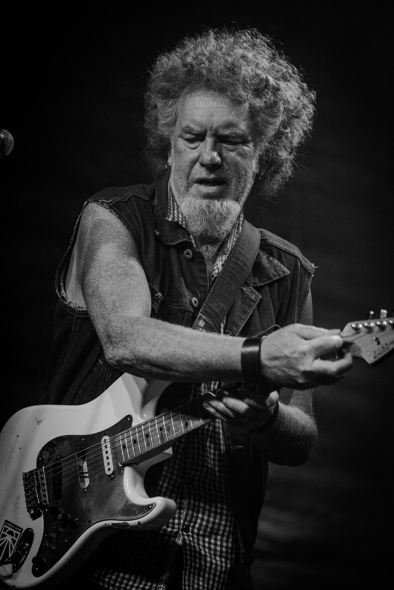 Black and white portrait of guitarist playing electric guitar during passionate stage performance.