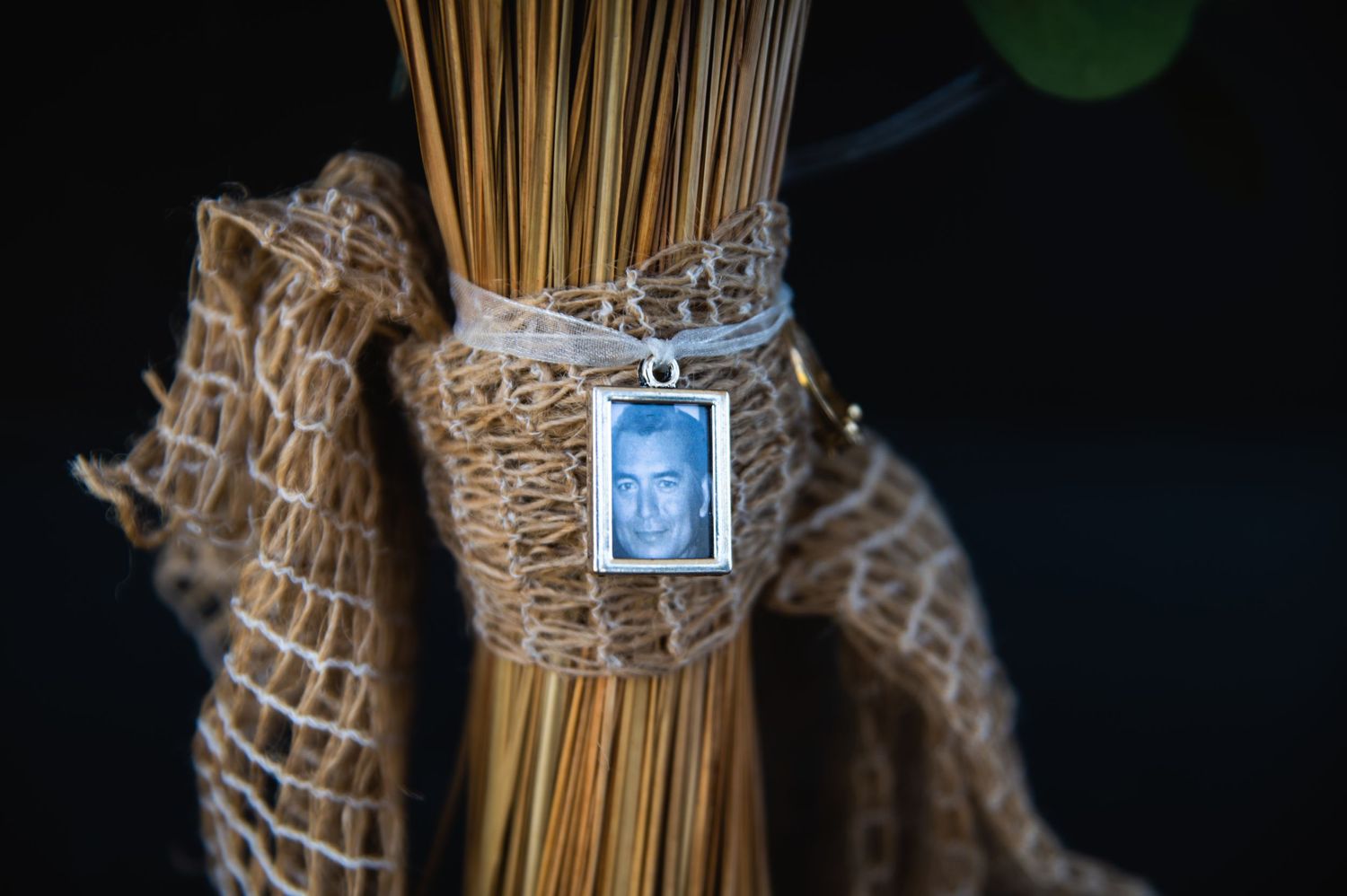 Wedding bouquet wrapped in twine with small memorial photo charm attached.