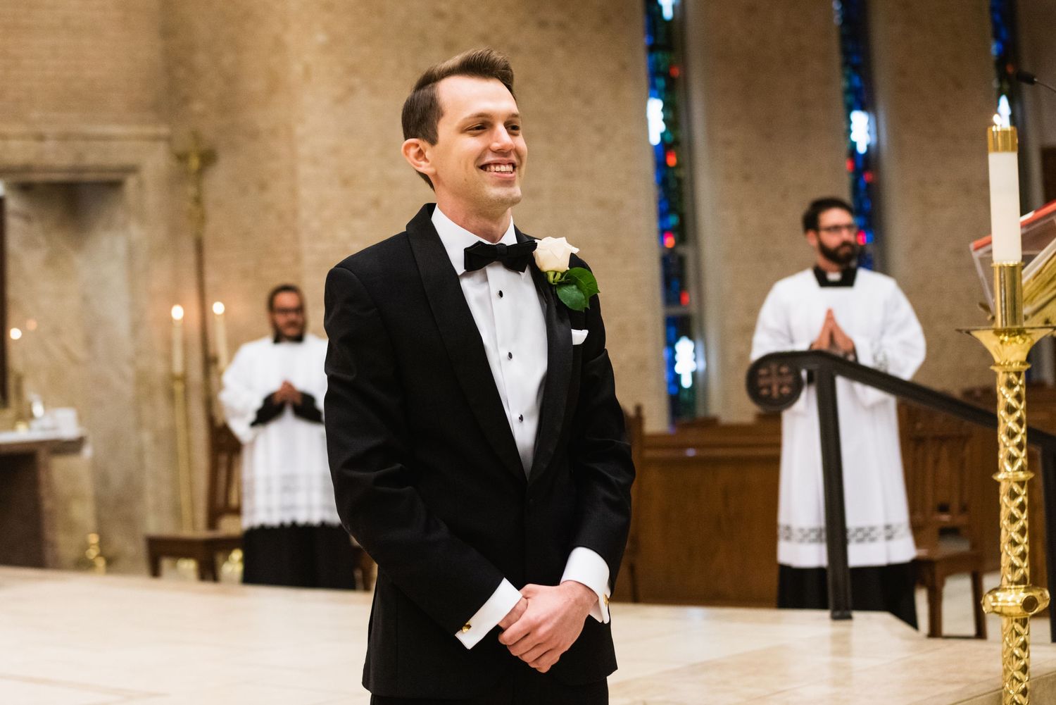 Groom in black tuxedo stands at altar while awaiting bride's arrival.