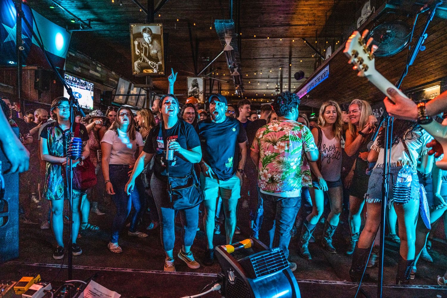 Concert audience enjoying live music under vibrant blue lighting in a small venue.