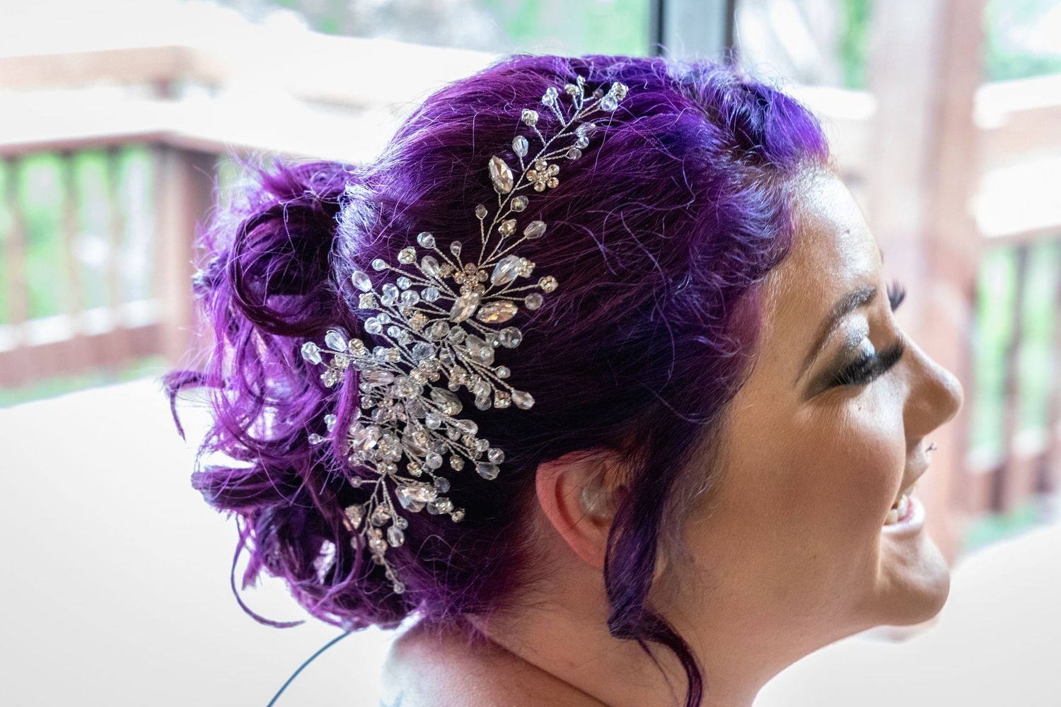 Elegant bridal hairstyle featuring purple curls adorned with crystal hair accessory.