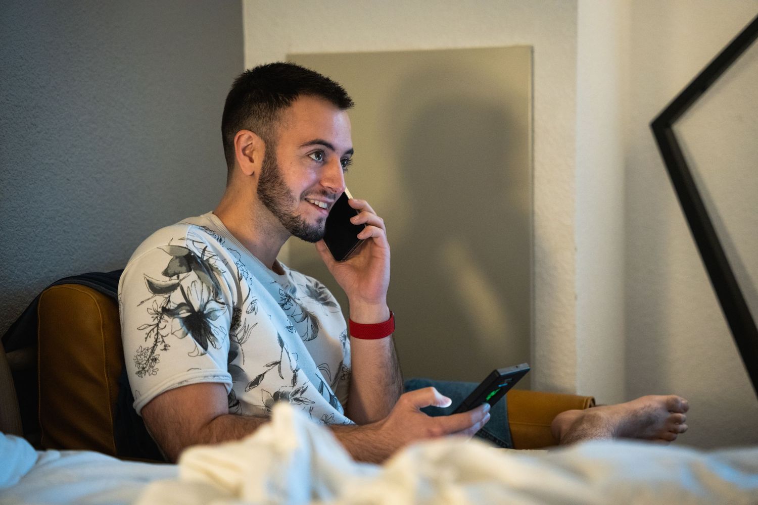 A person relaxes on a couch while using their phone and smiling.
