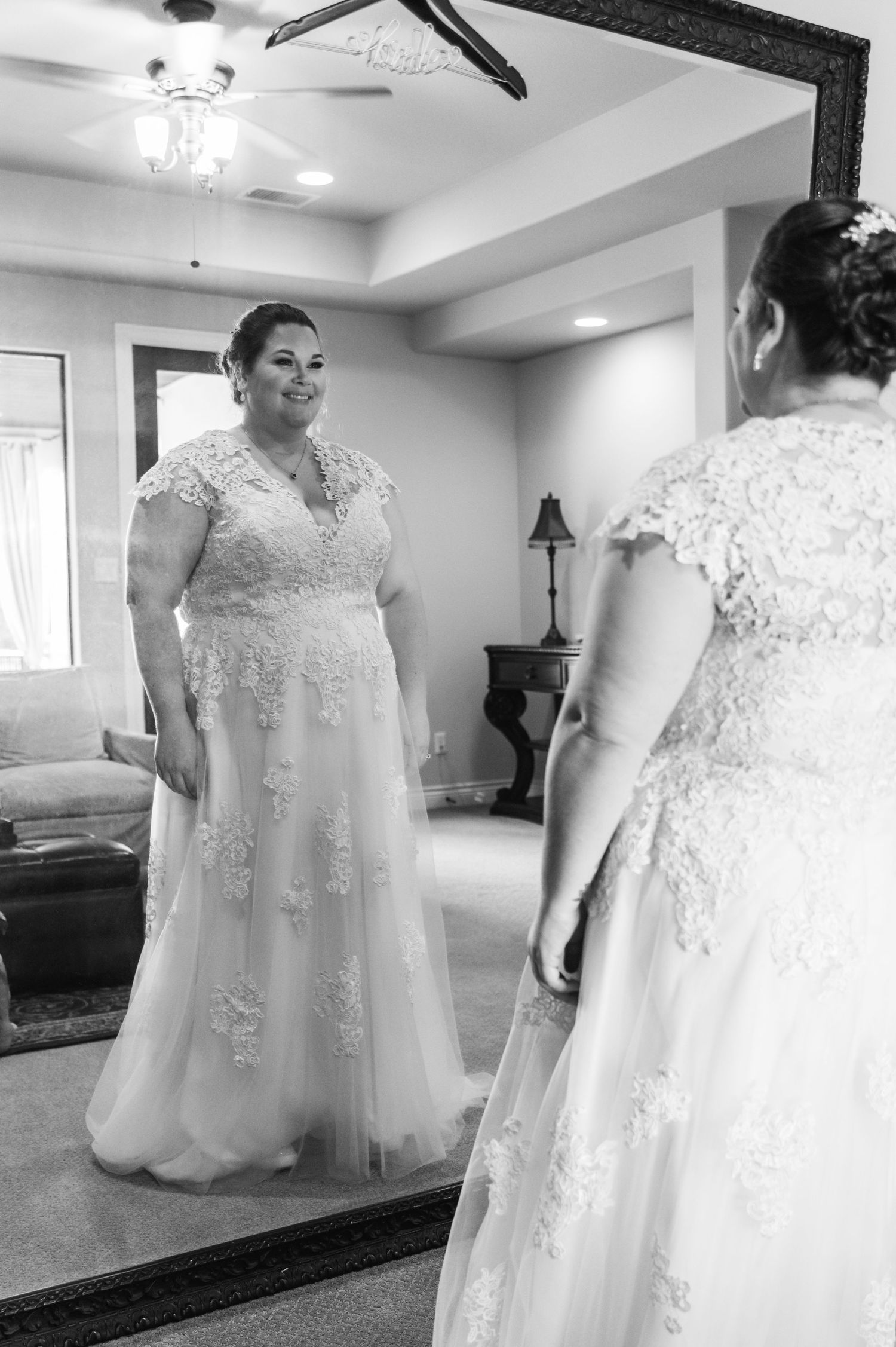 Elegant wedding dress with lace details reflected in full-length mirror.