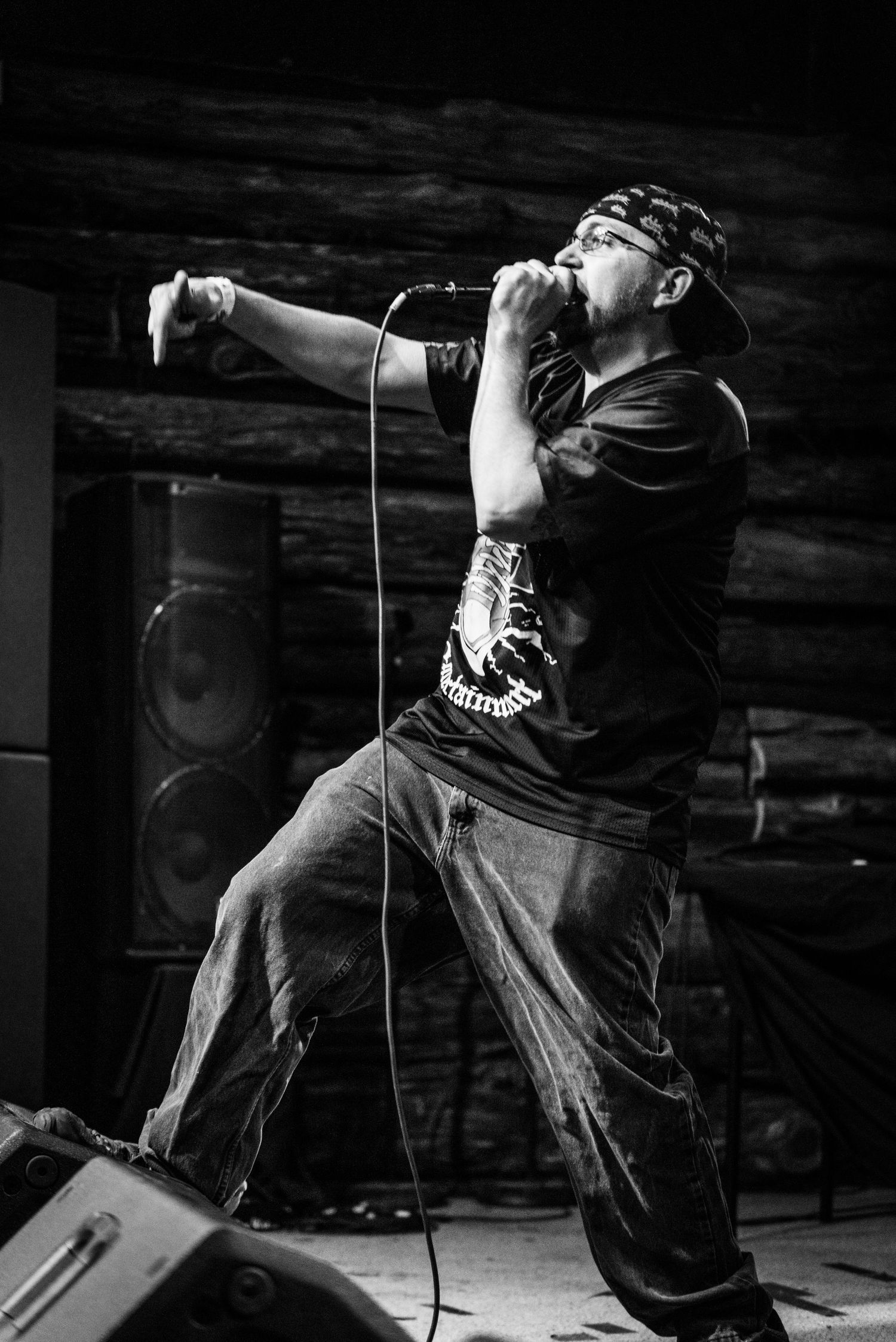Black and white photo of performer in bandana singing passionately on stage.