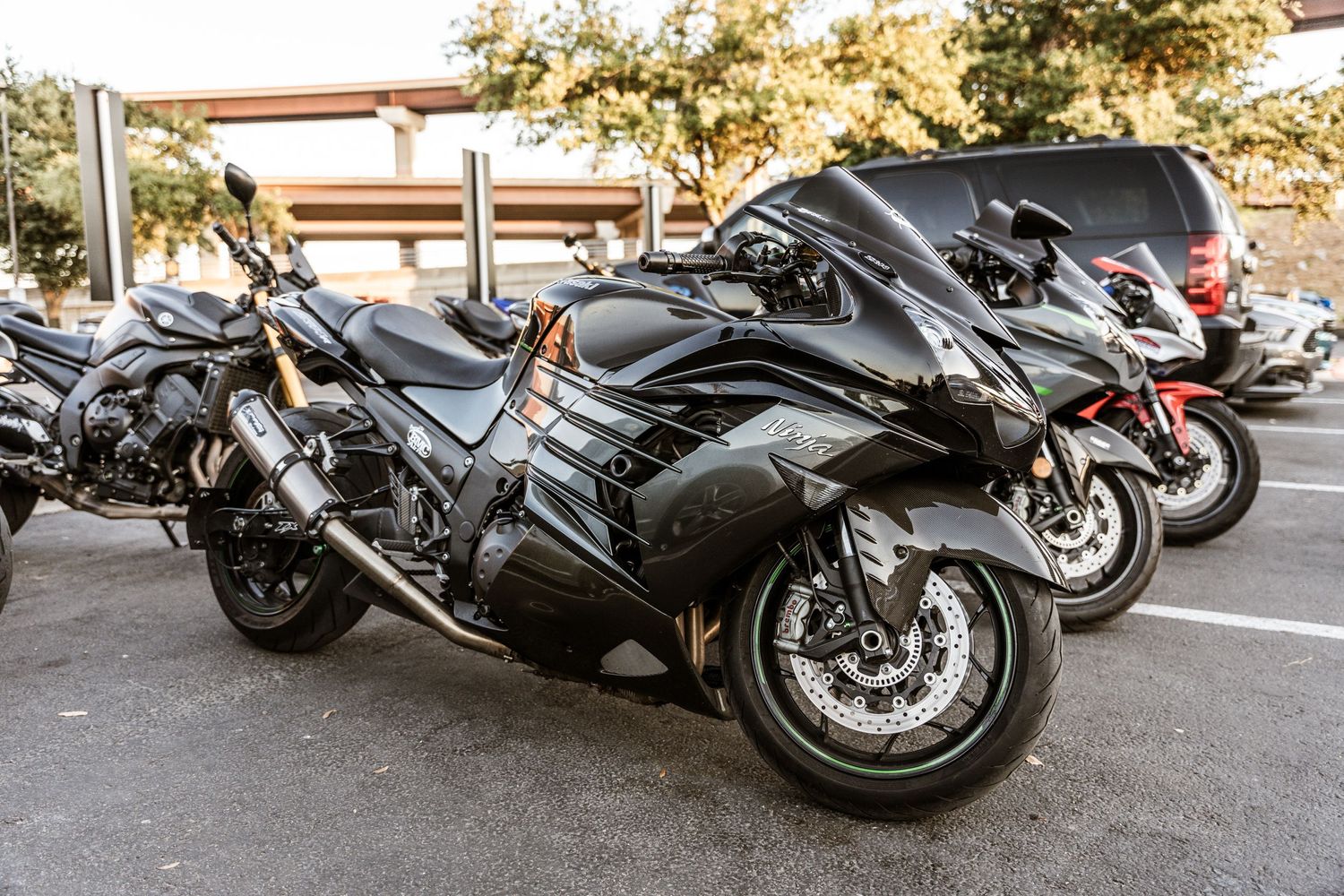 Row of black sport motorcycles parked in a retail parking lot.